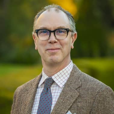 a person wearing glasses and a suit