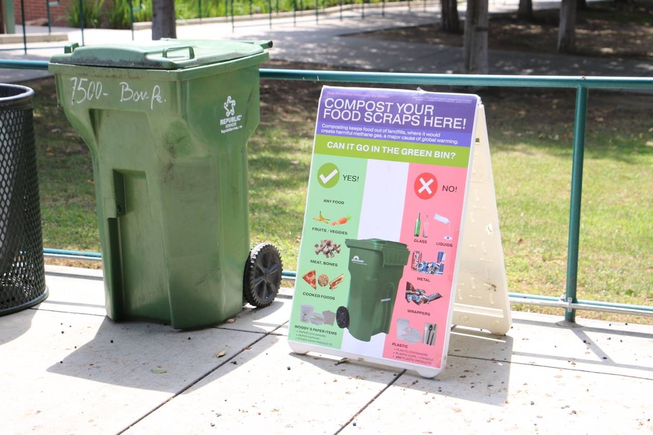 a sign next to a green trash can