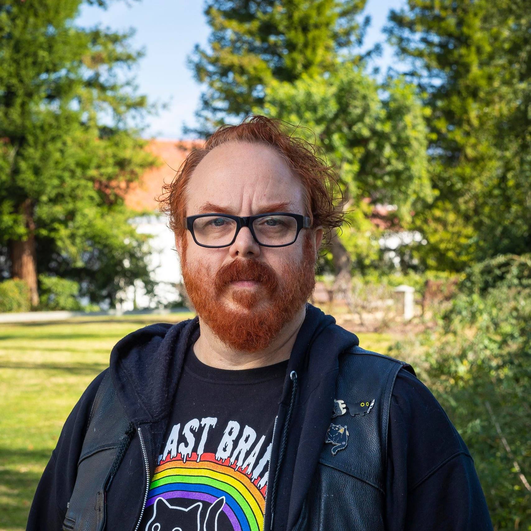 a person with red hair and beard standing in front of trees