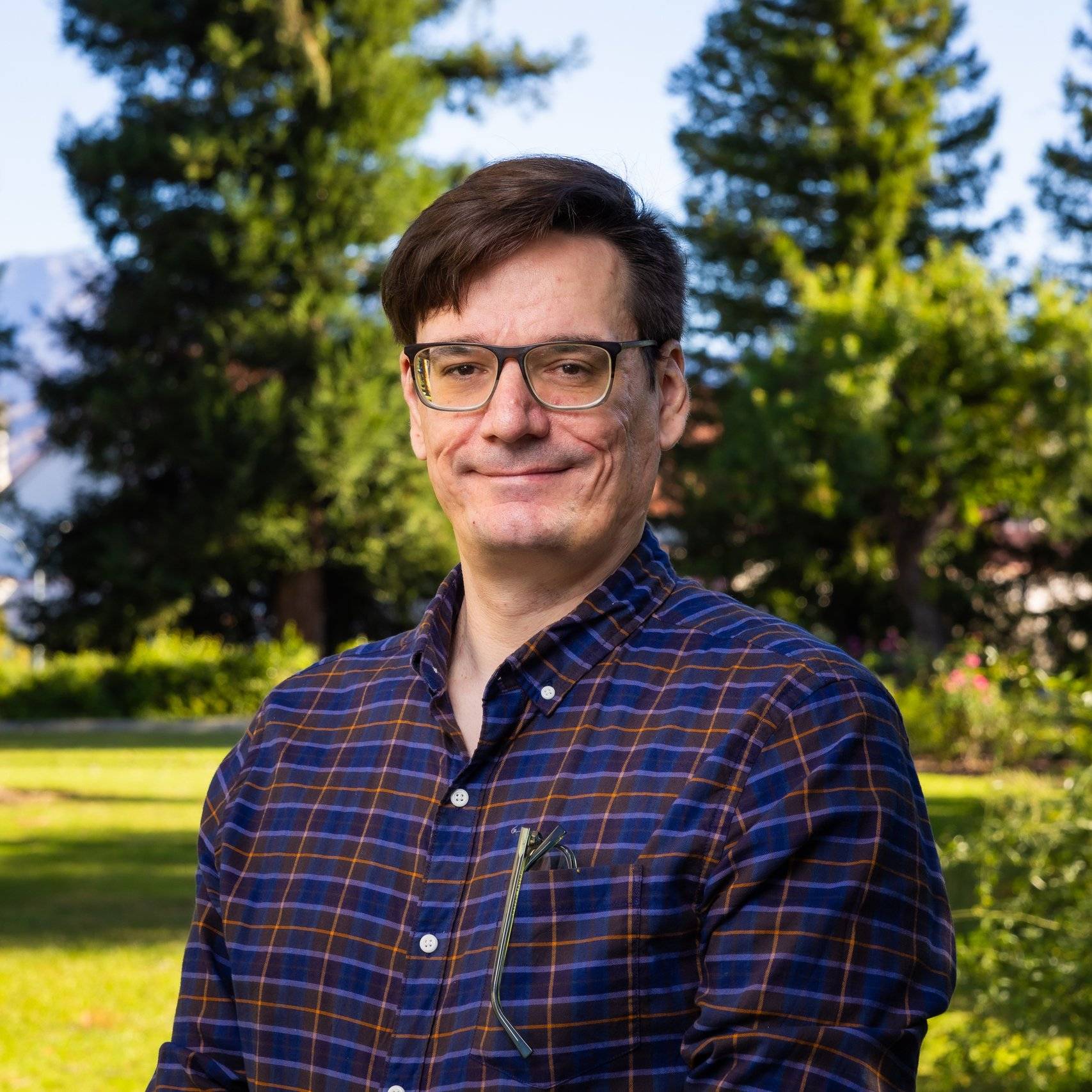 a person wearing glasses and a blue plaid shirt