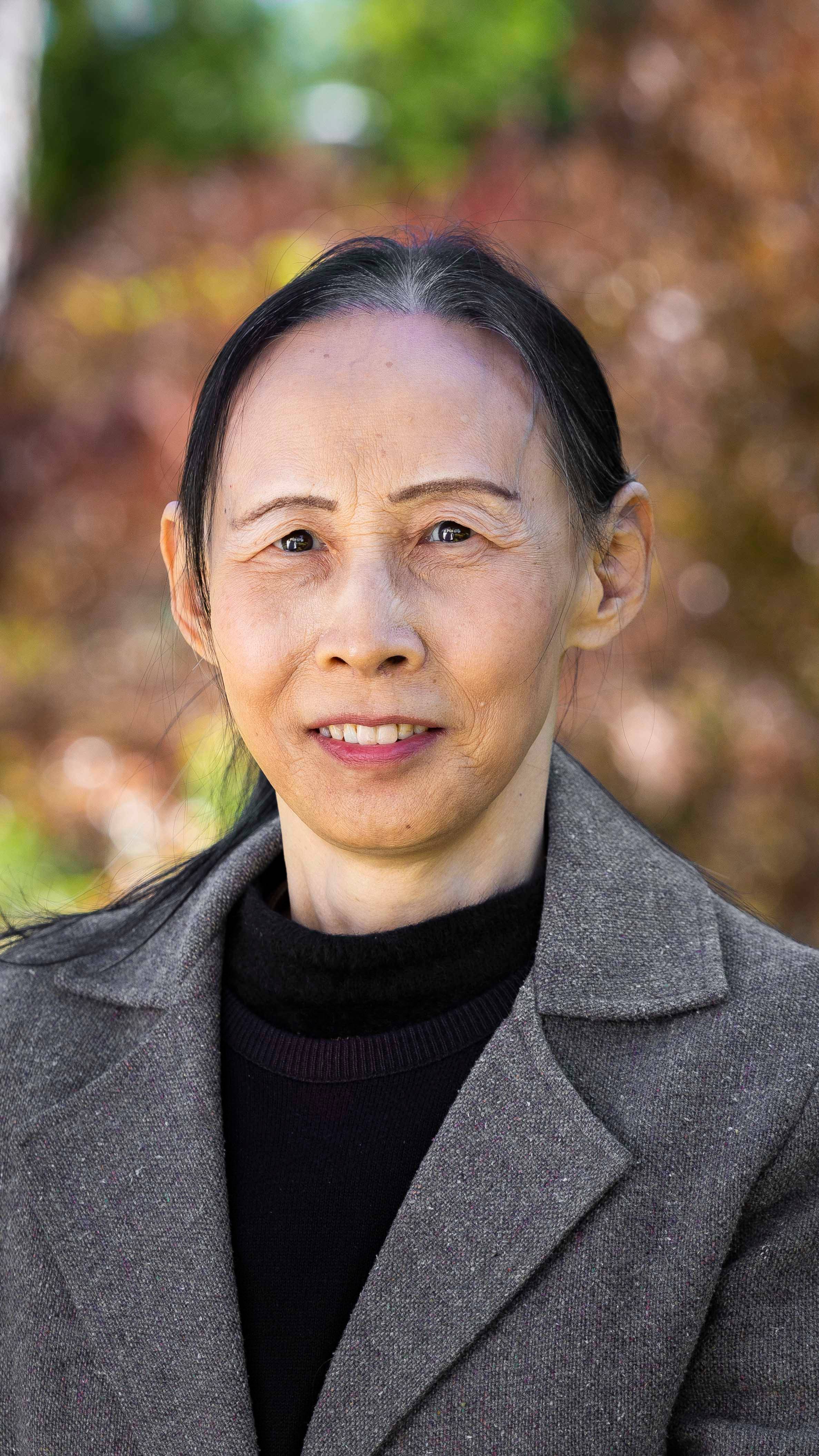 a person with dark hair wearing a grey coat