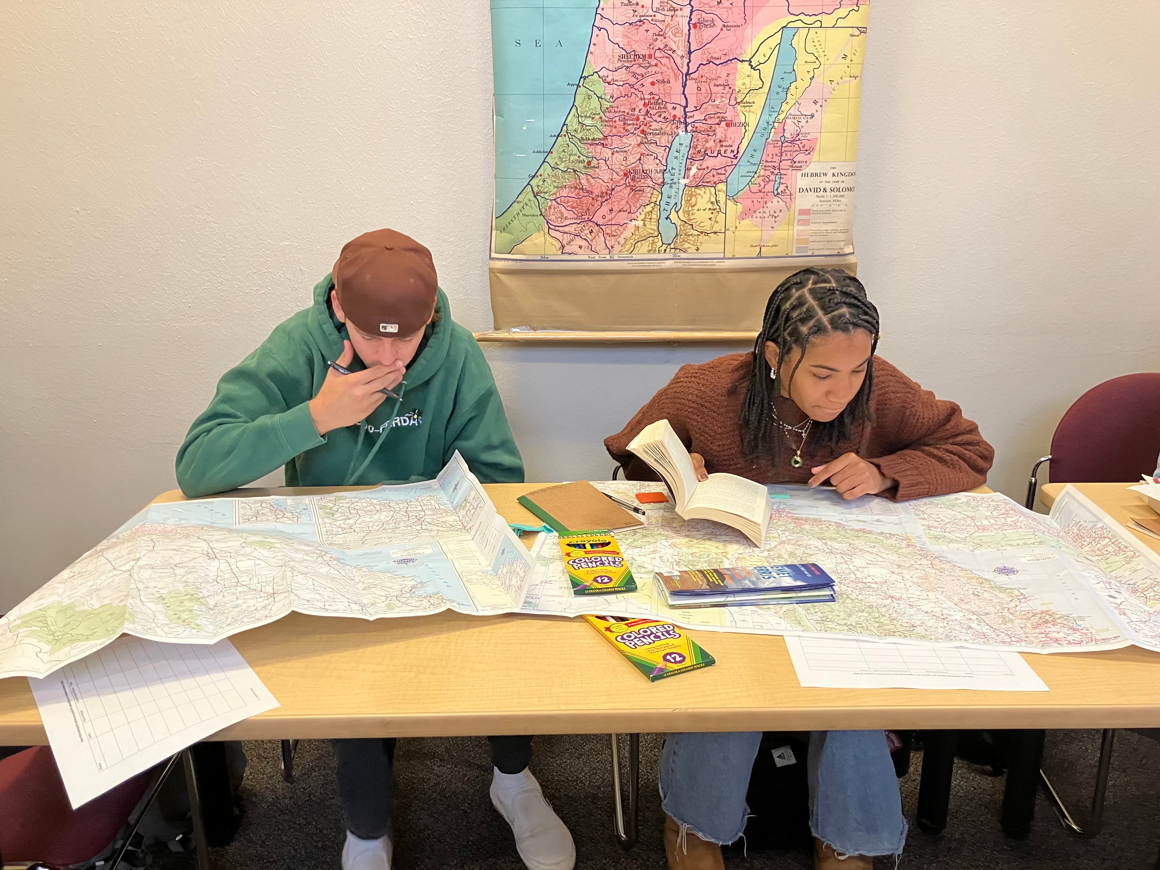 a person and person sitting at a table with maps