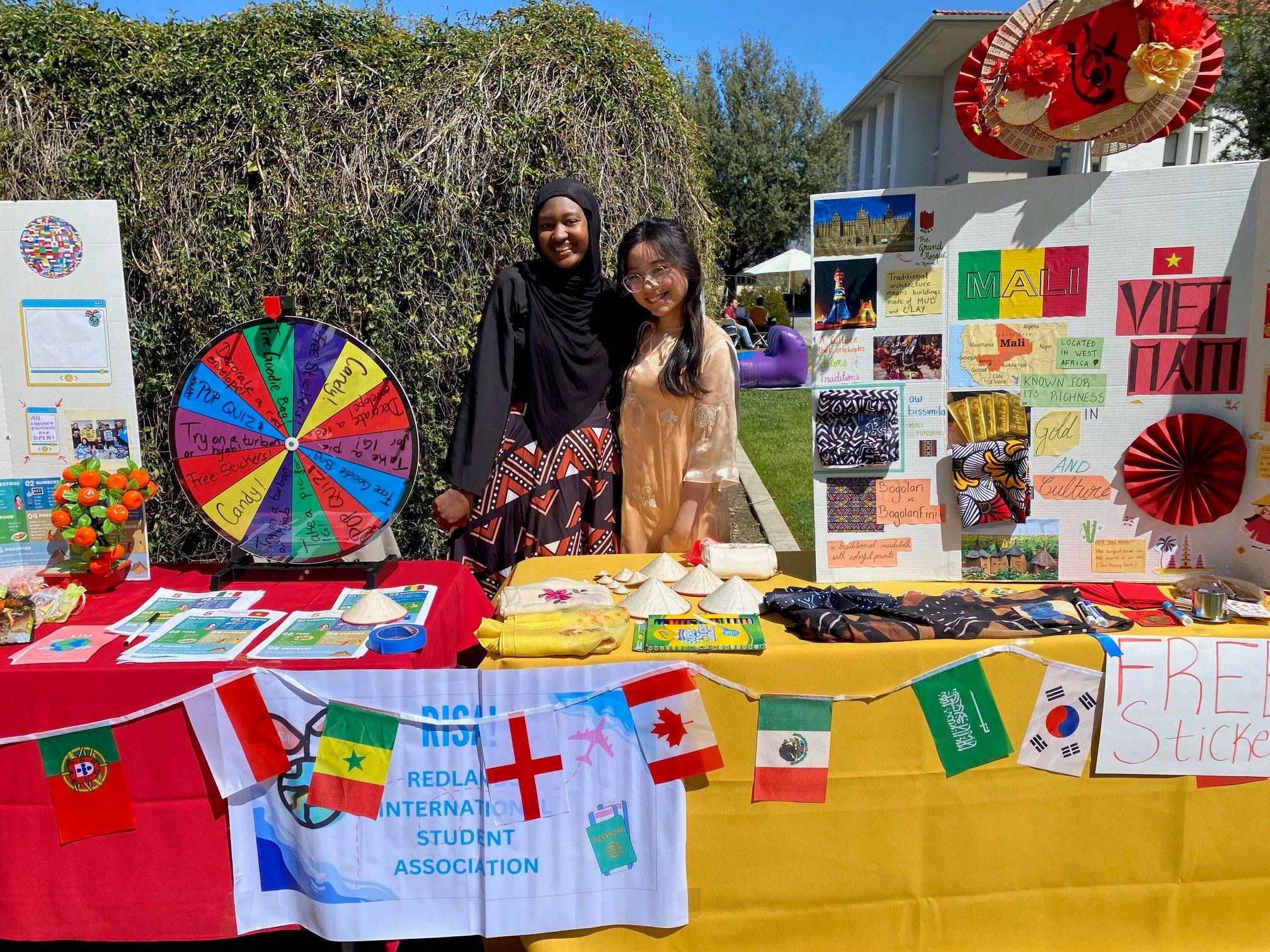 two women standing next to a table with flags and a wheel