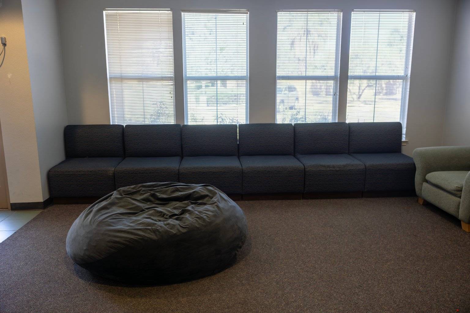 a large bean bag in a room with a long couch and windows