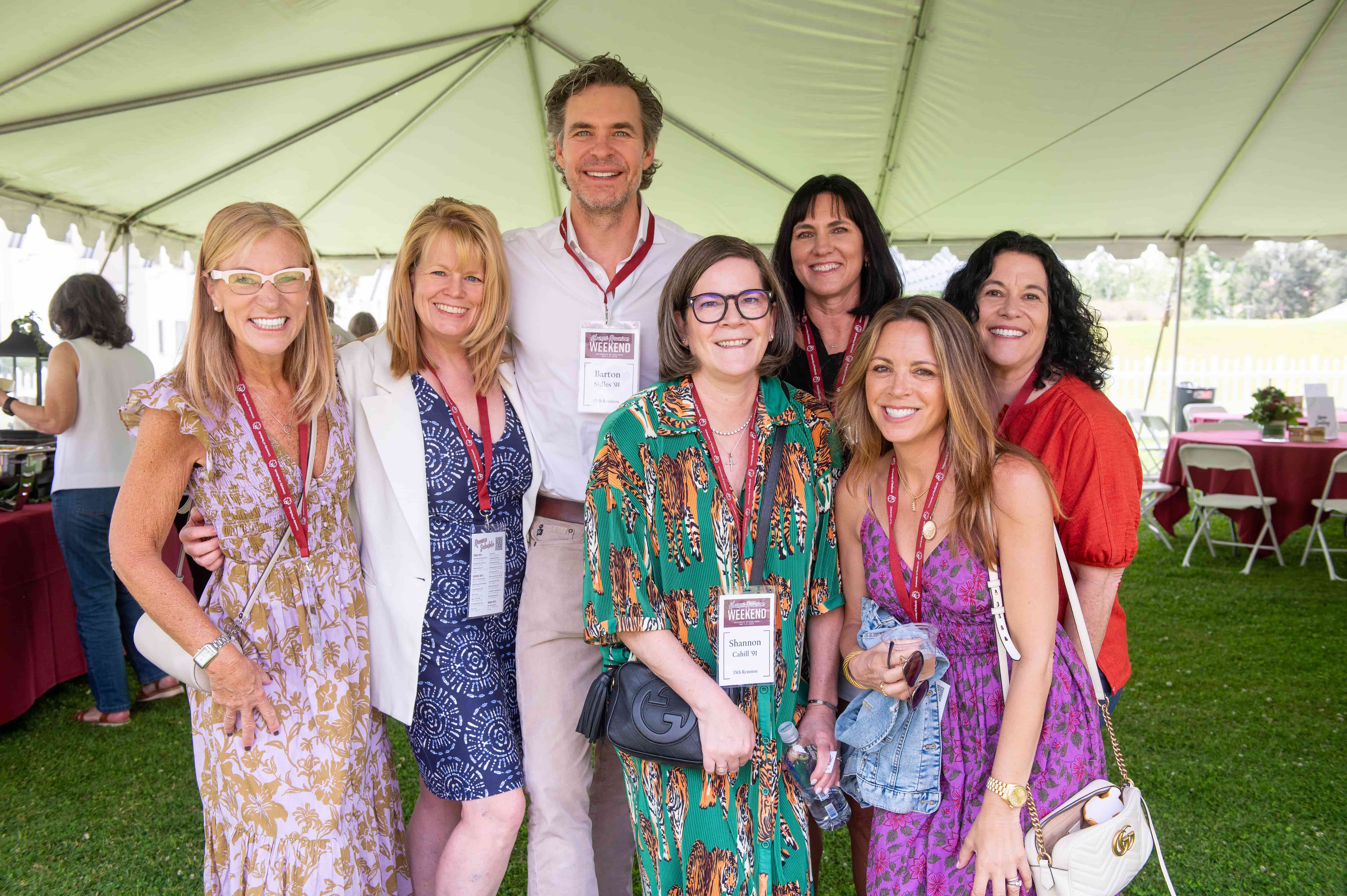 a group of alumni standing under a tent at alumni reunion weekend.