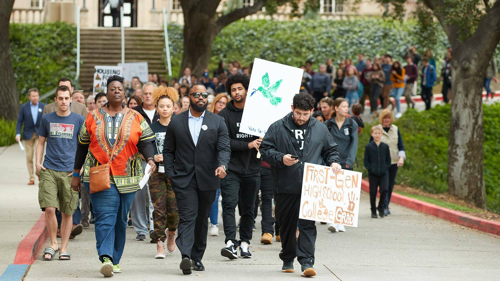 a group of people walking down a street holding signs