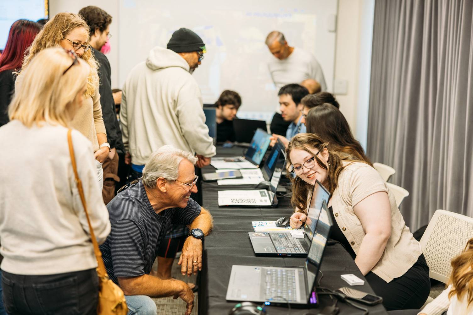 a group of people sitting at a table with laptops