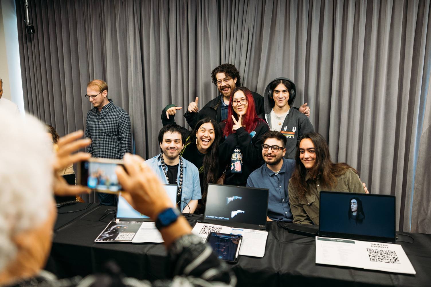 a group of people sitting around a table with laptops
