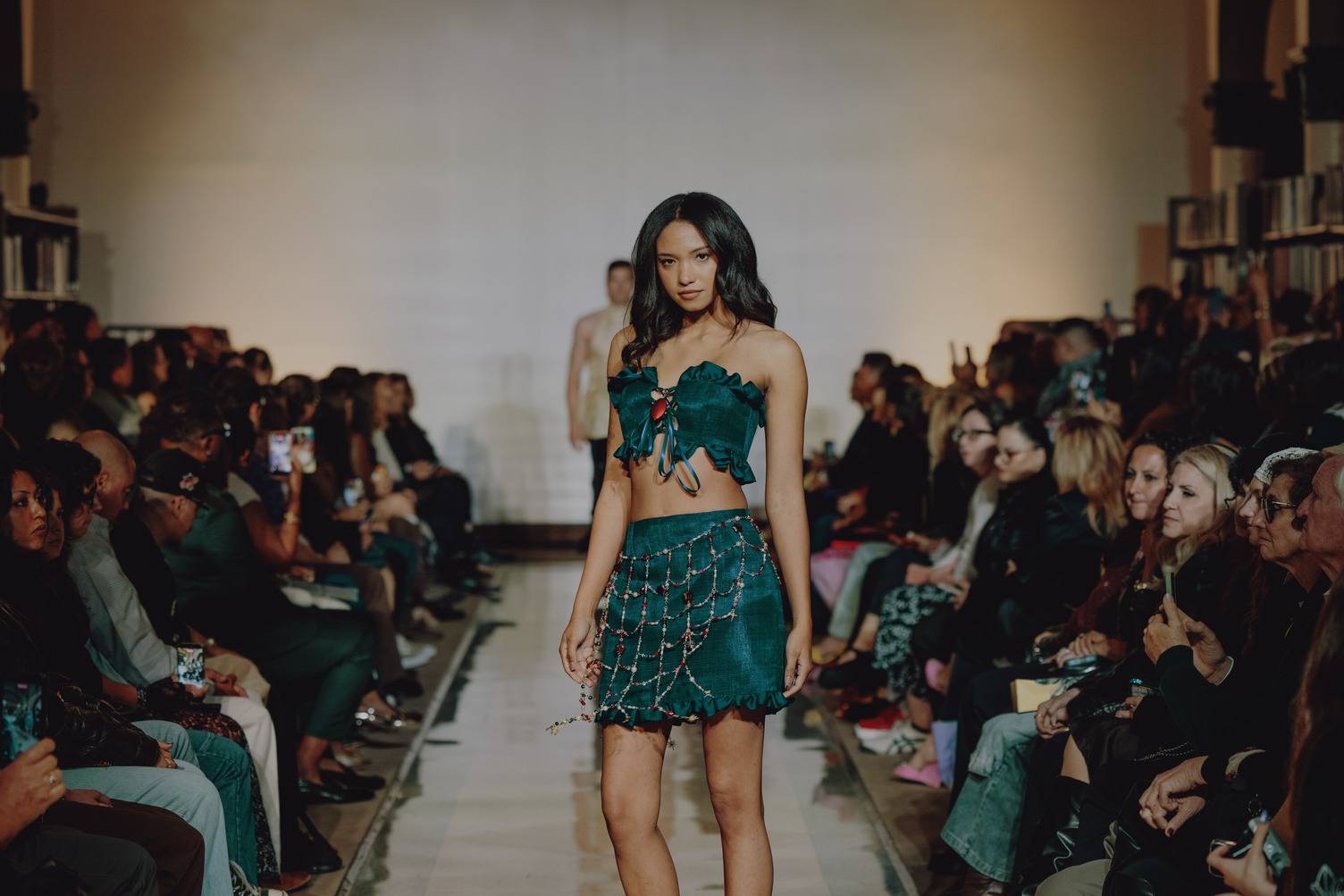a person walking down a runway wearing a green outfit