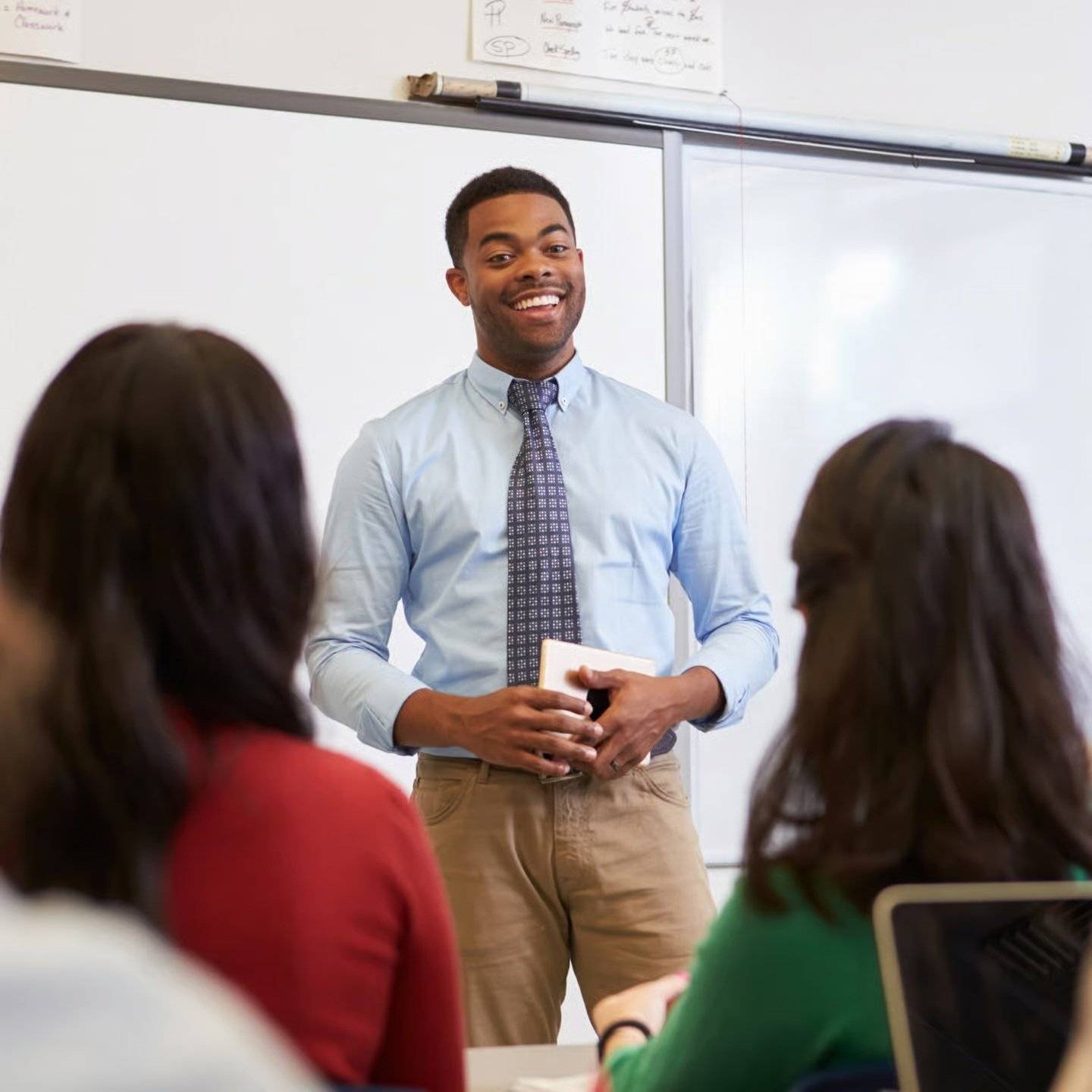 A teacher leads a lesson at the front of their classroom.