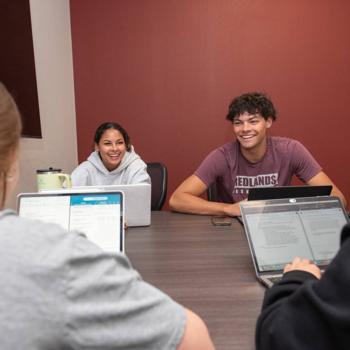 a group of people sitting at a table with laptops
