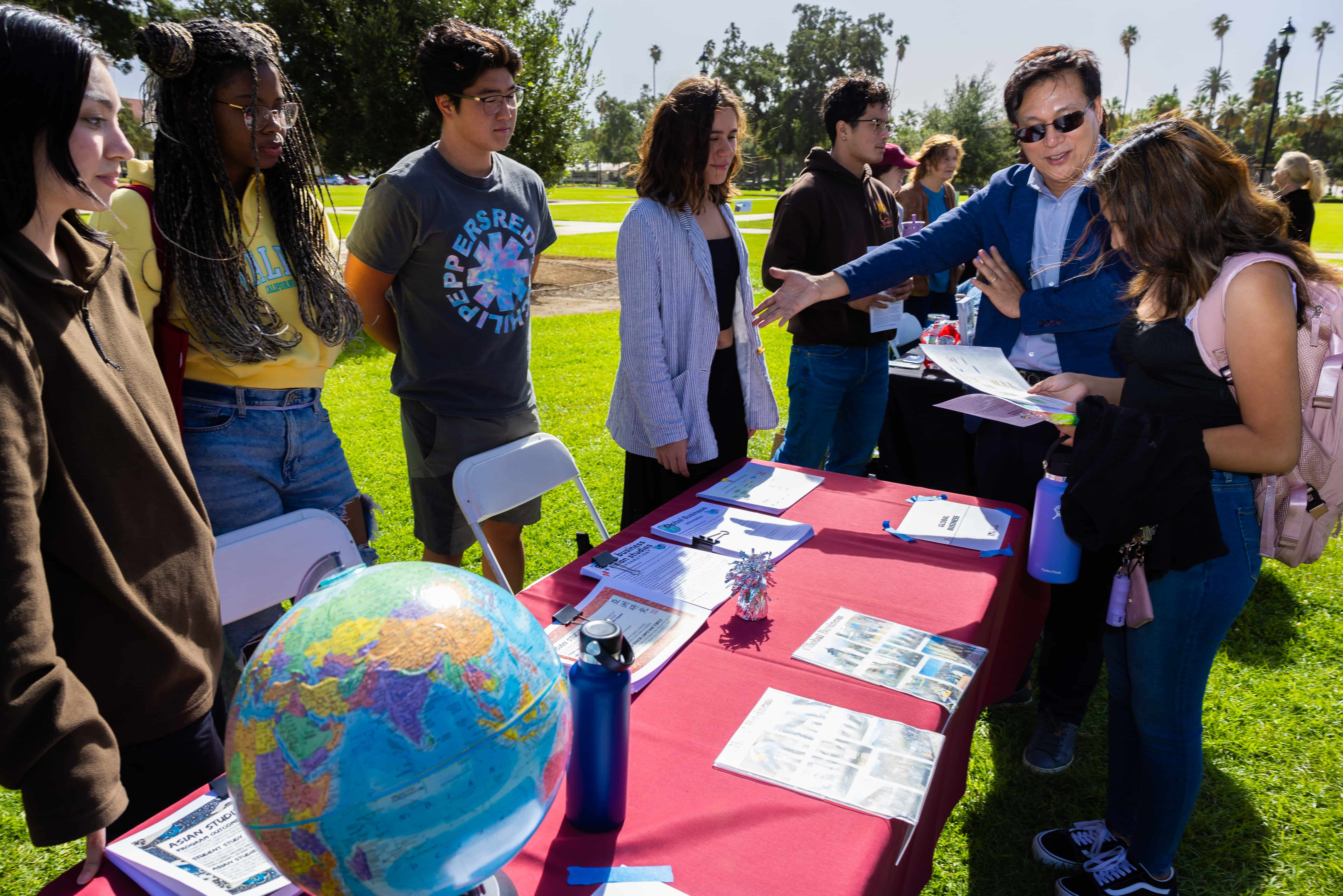 a group of people standing around a table with papers and a globe