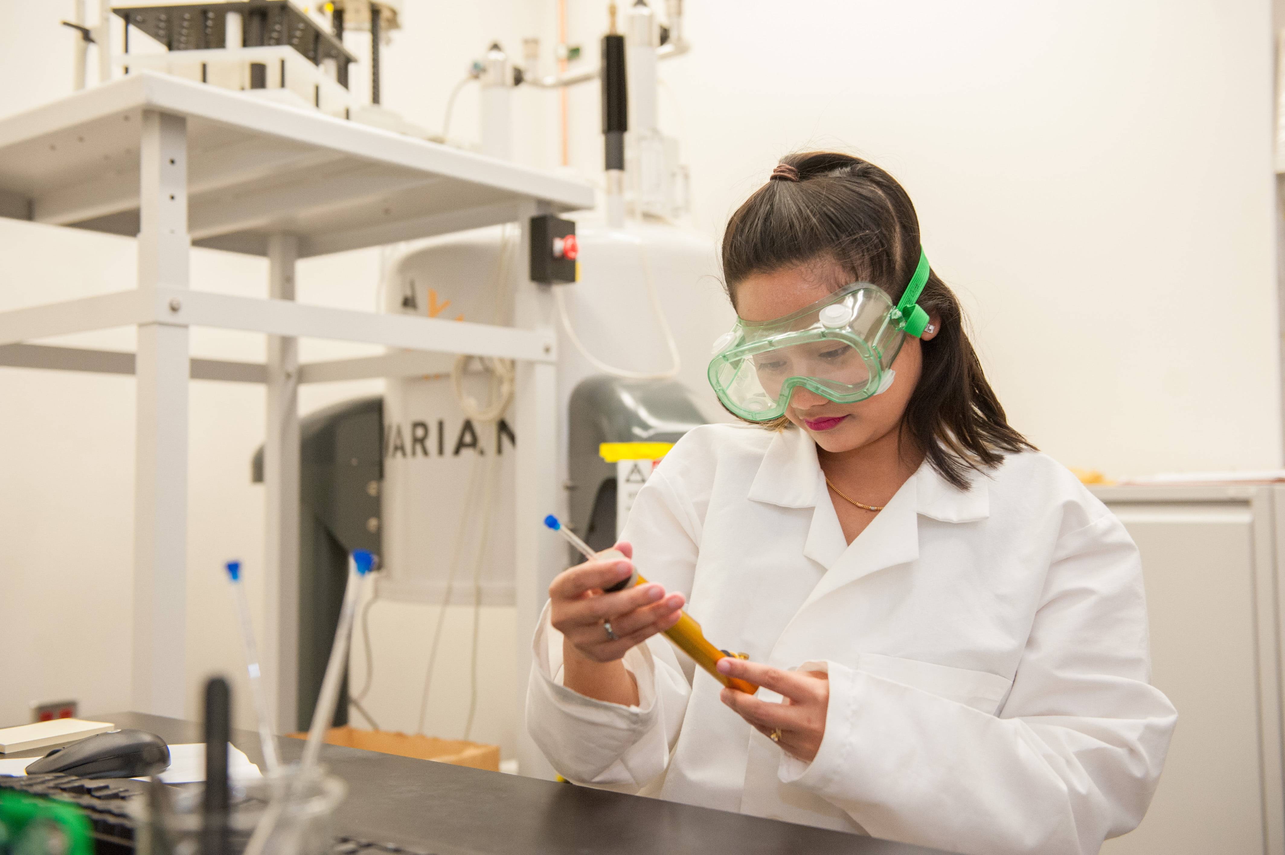 a person wearing safety goggles and holding a tube