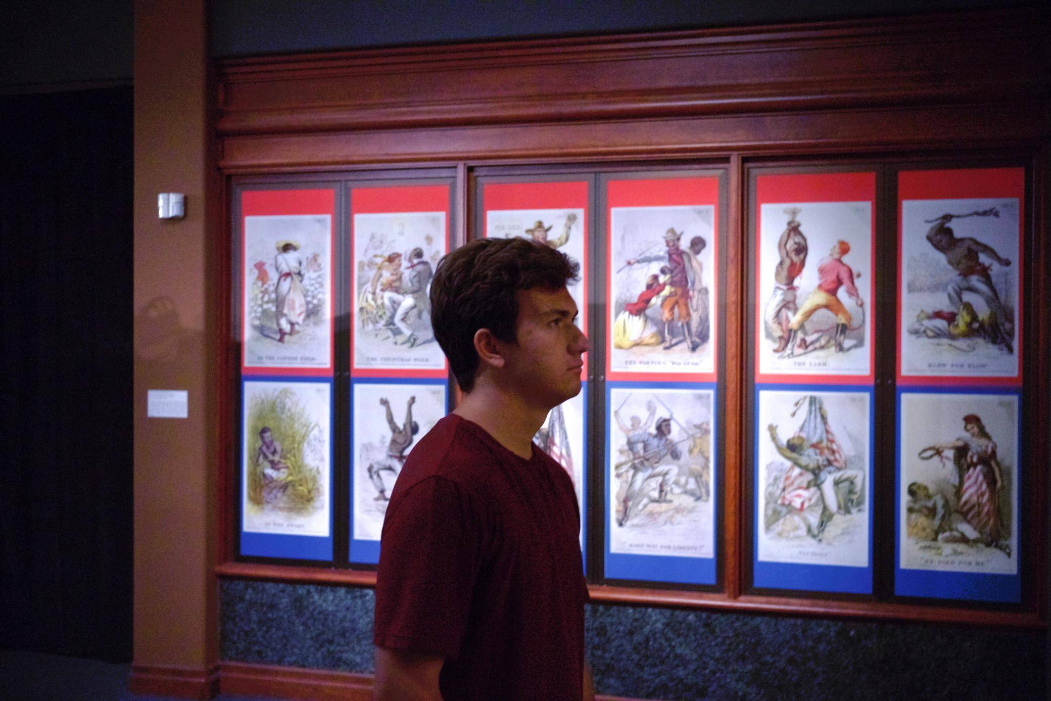a person standing in front of a wall of paintings