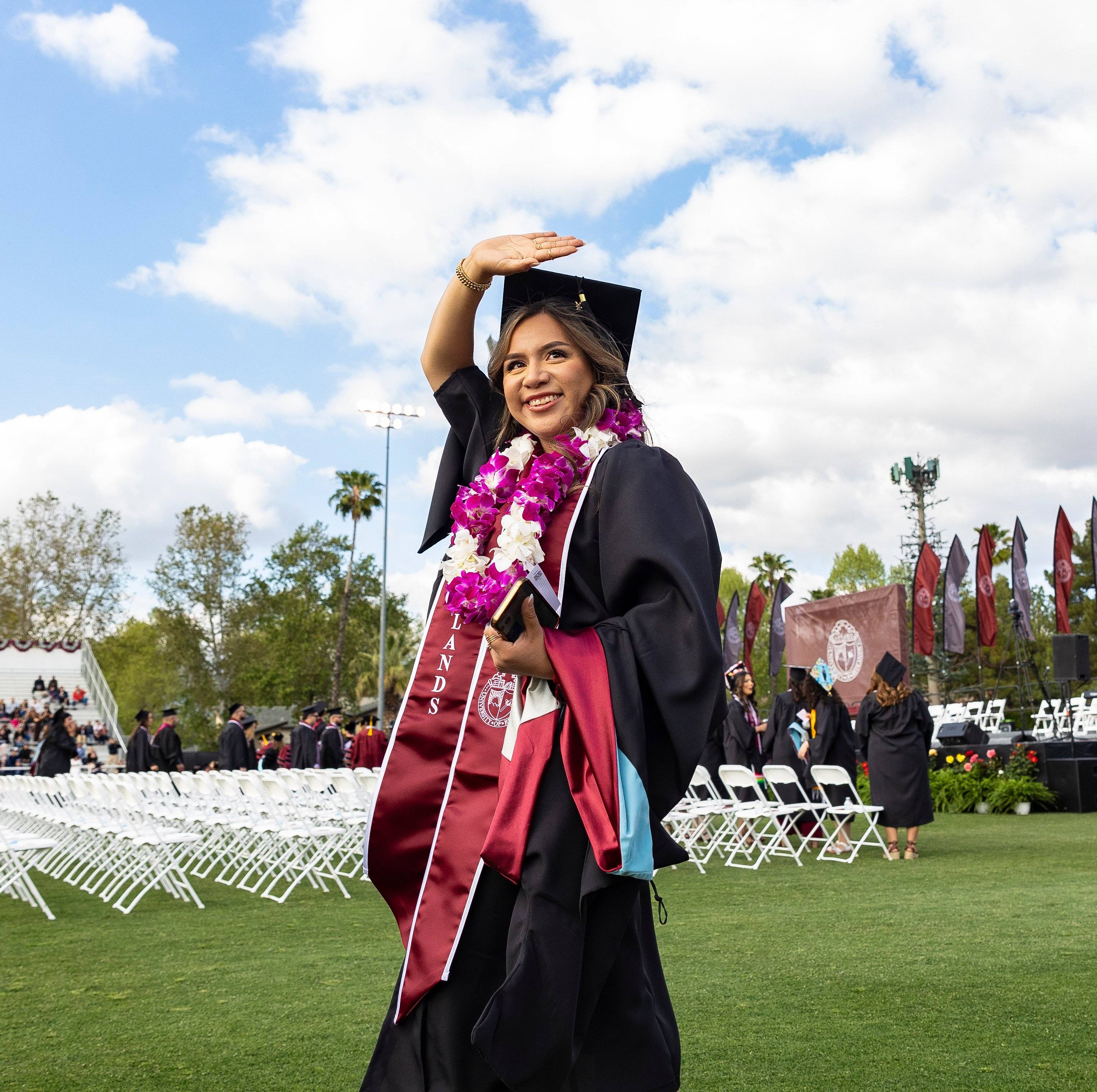 a person in a graduation gown and cap waving