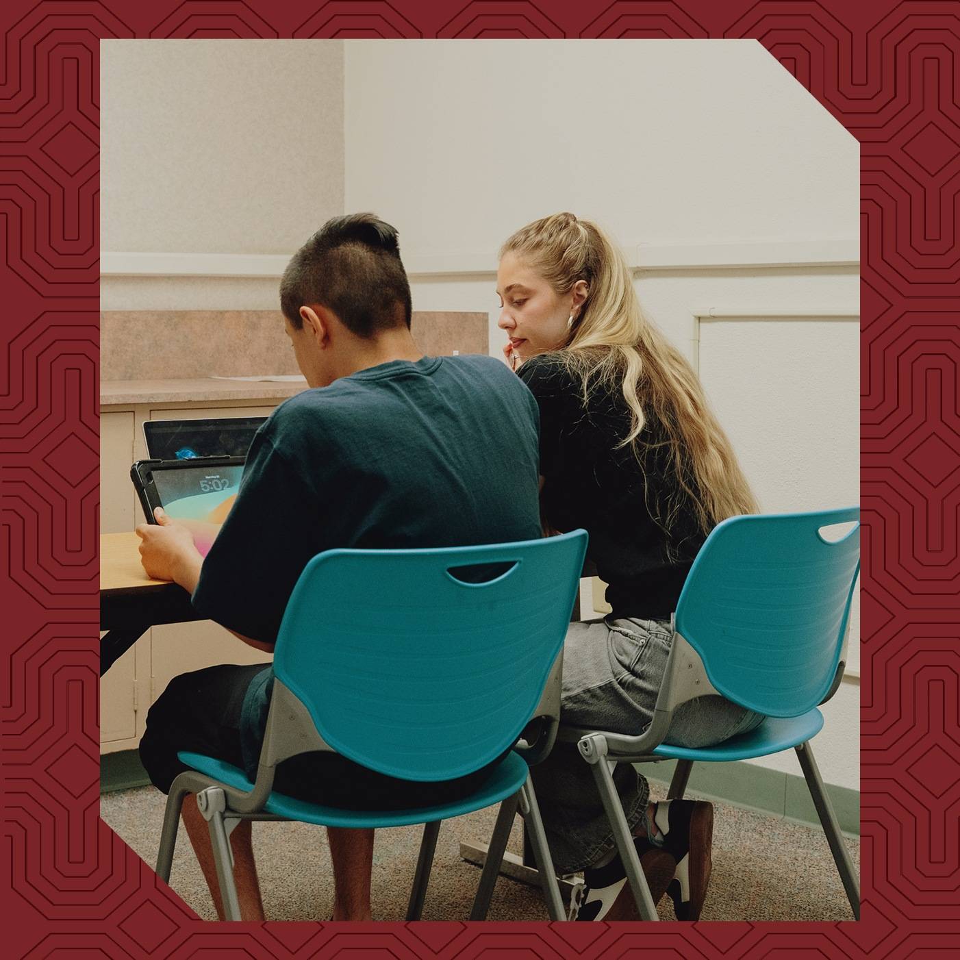 a person and person sitting at a table looking at a laptop