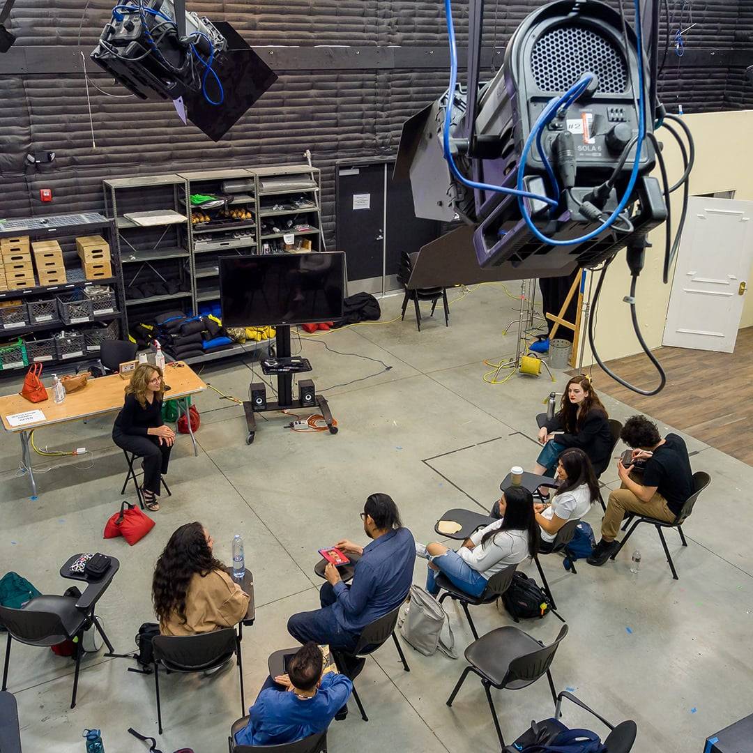 a group of people sitting in chairs in a room with a large projector