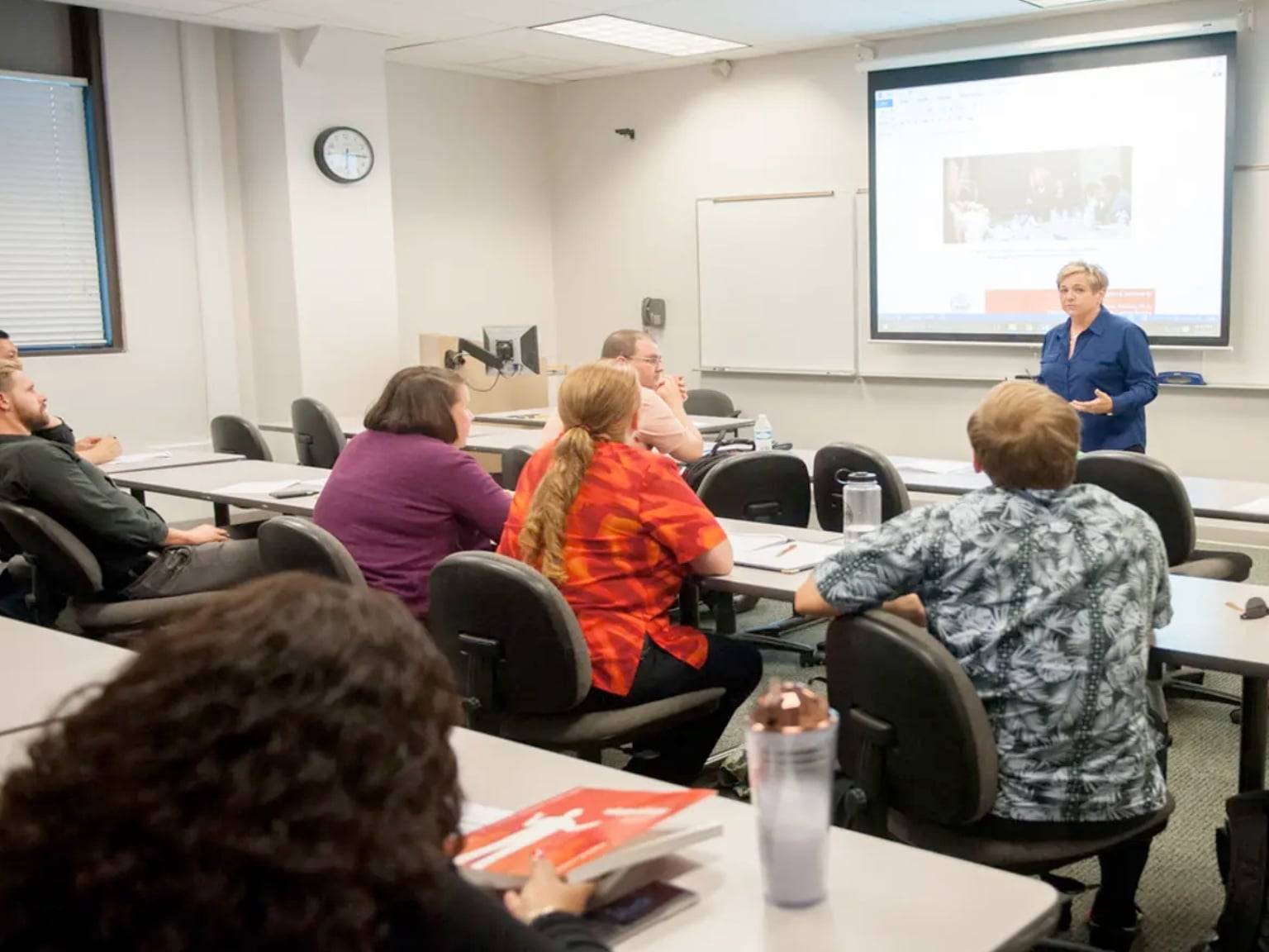 a person standing in front of a screen in a classroom