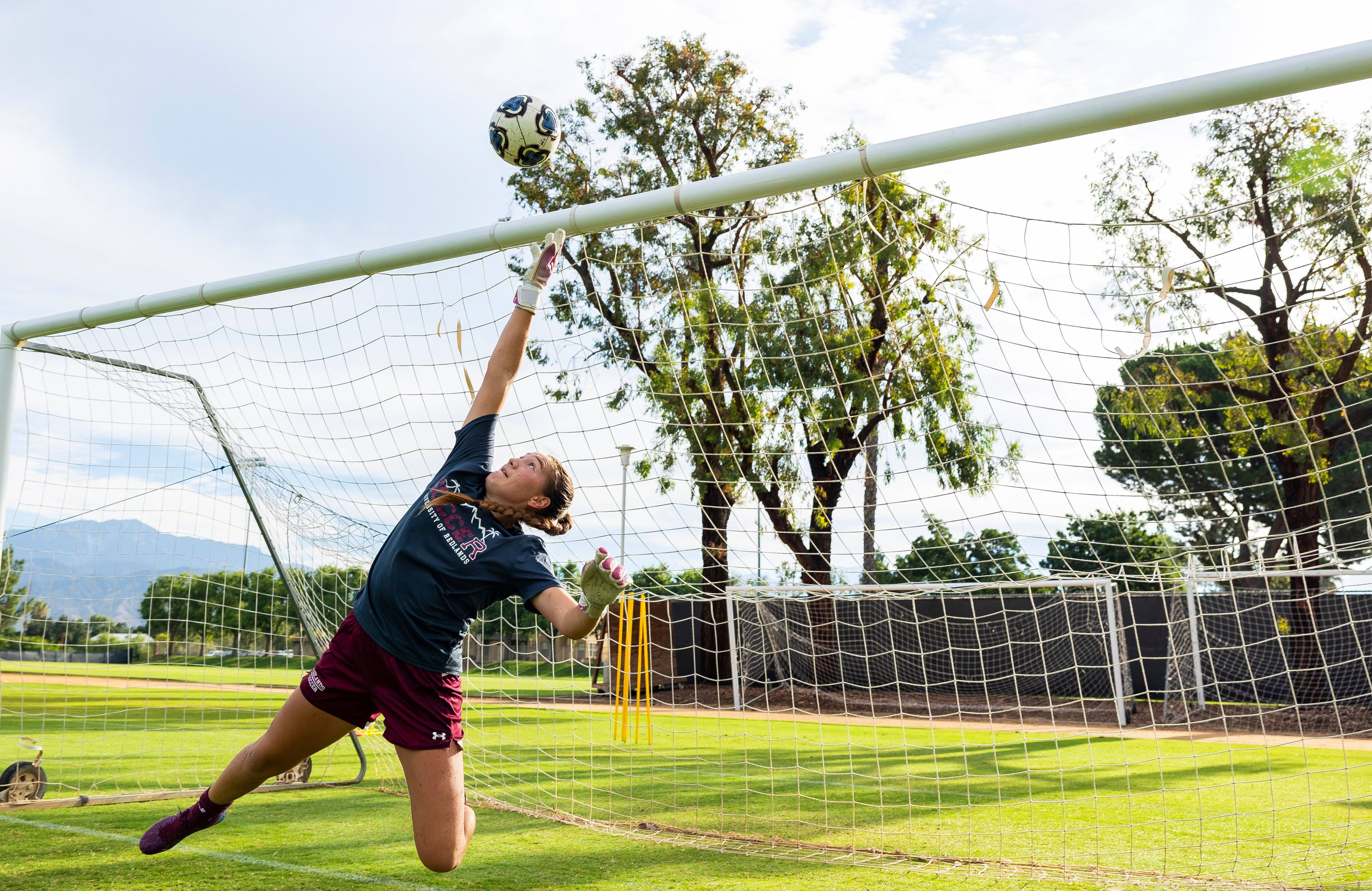 a person in a football uniform reaching for a football ball