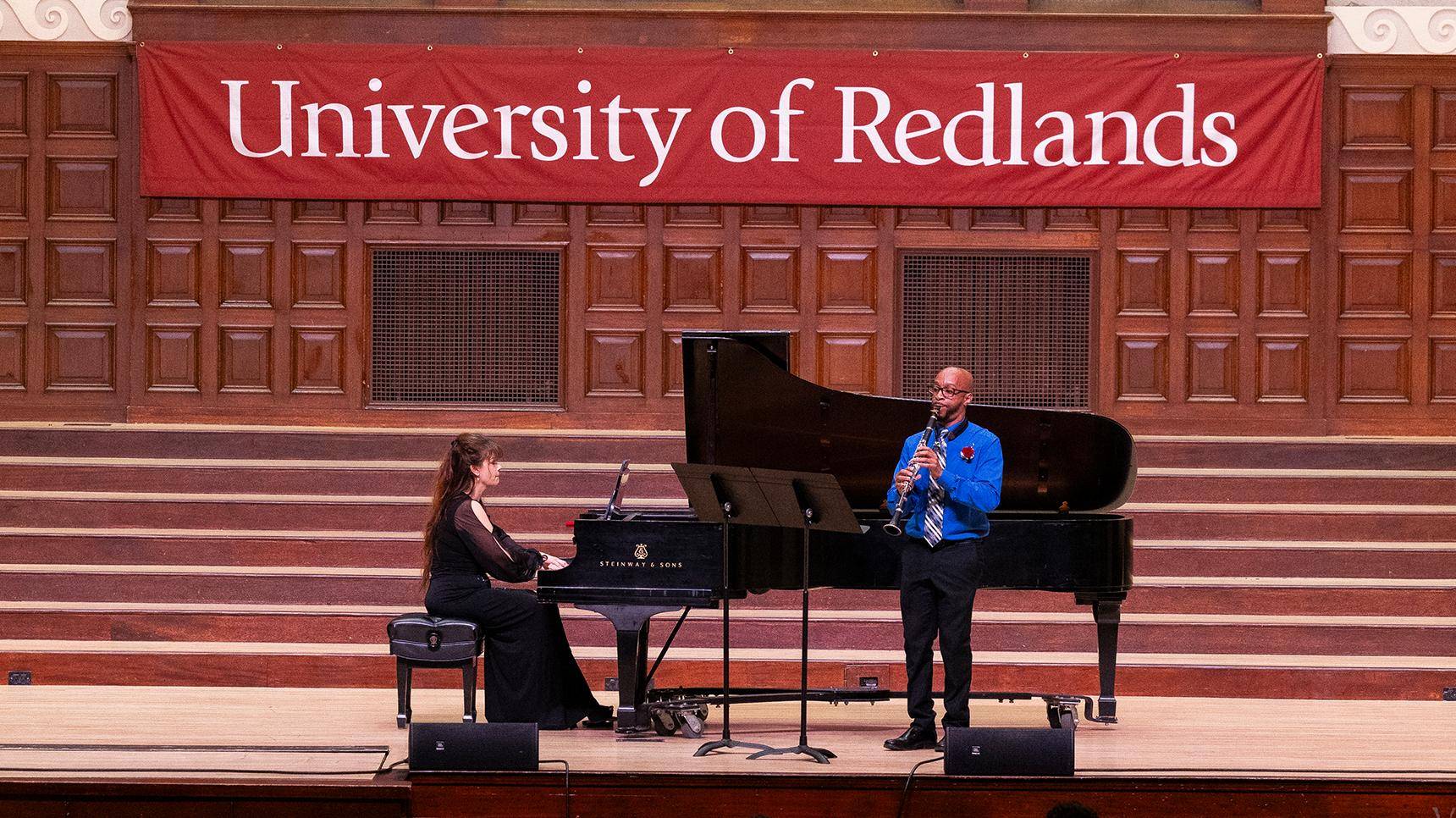 a person playing a flute on a stage with a person sitting on a piano