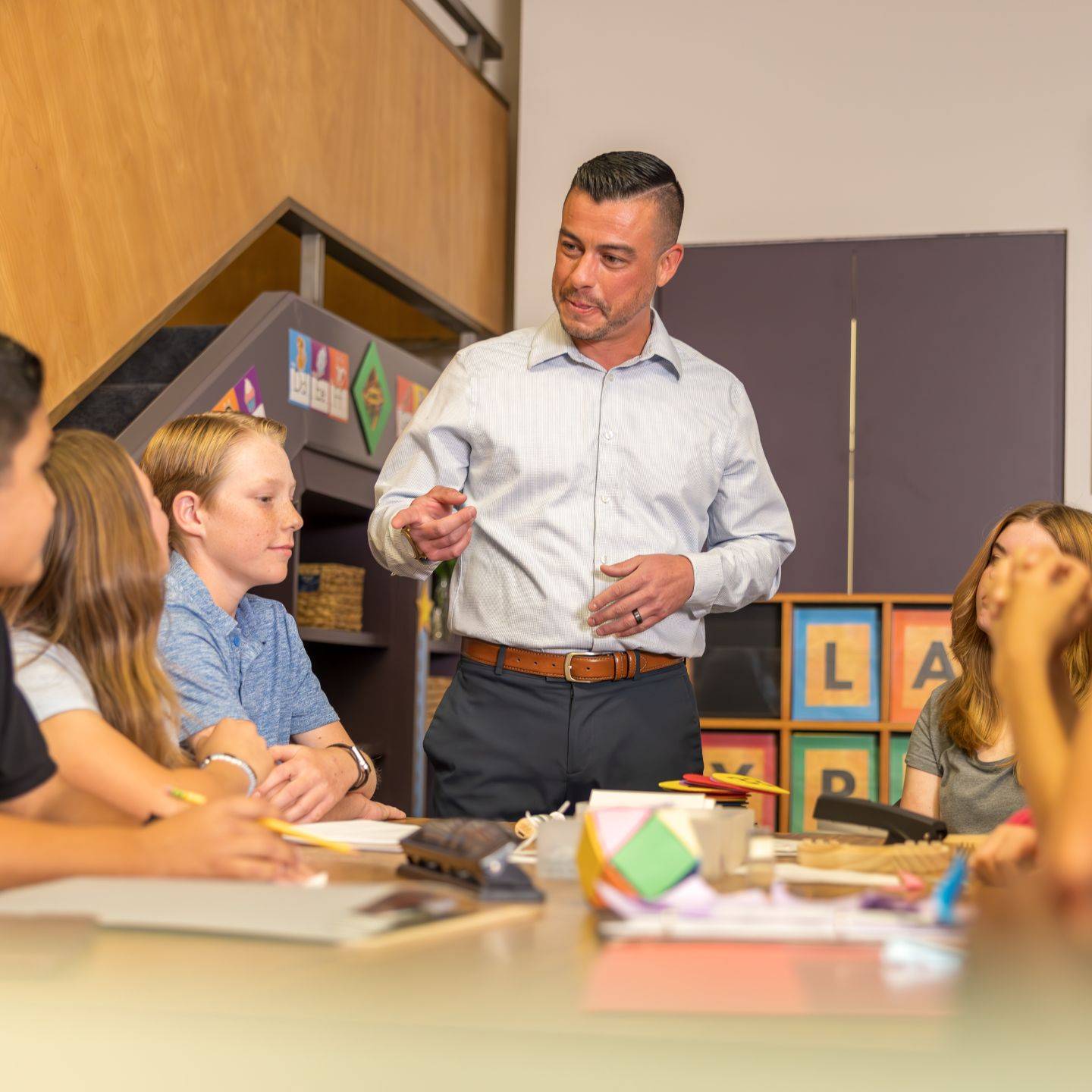 A teacher provides instructions to a group of students during a classroom activity.
