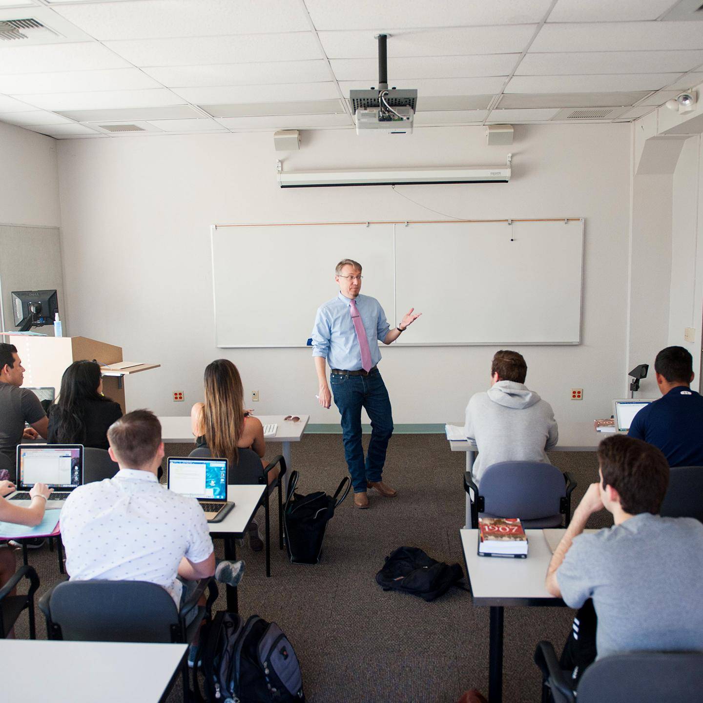 a person standing in front of a classroom with a group of people