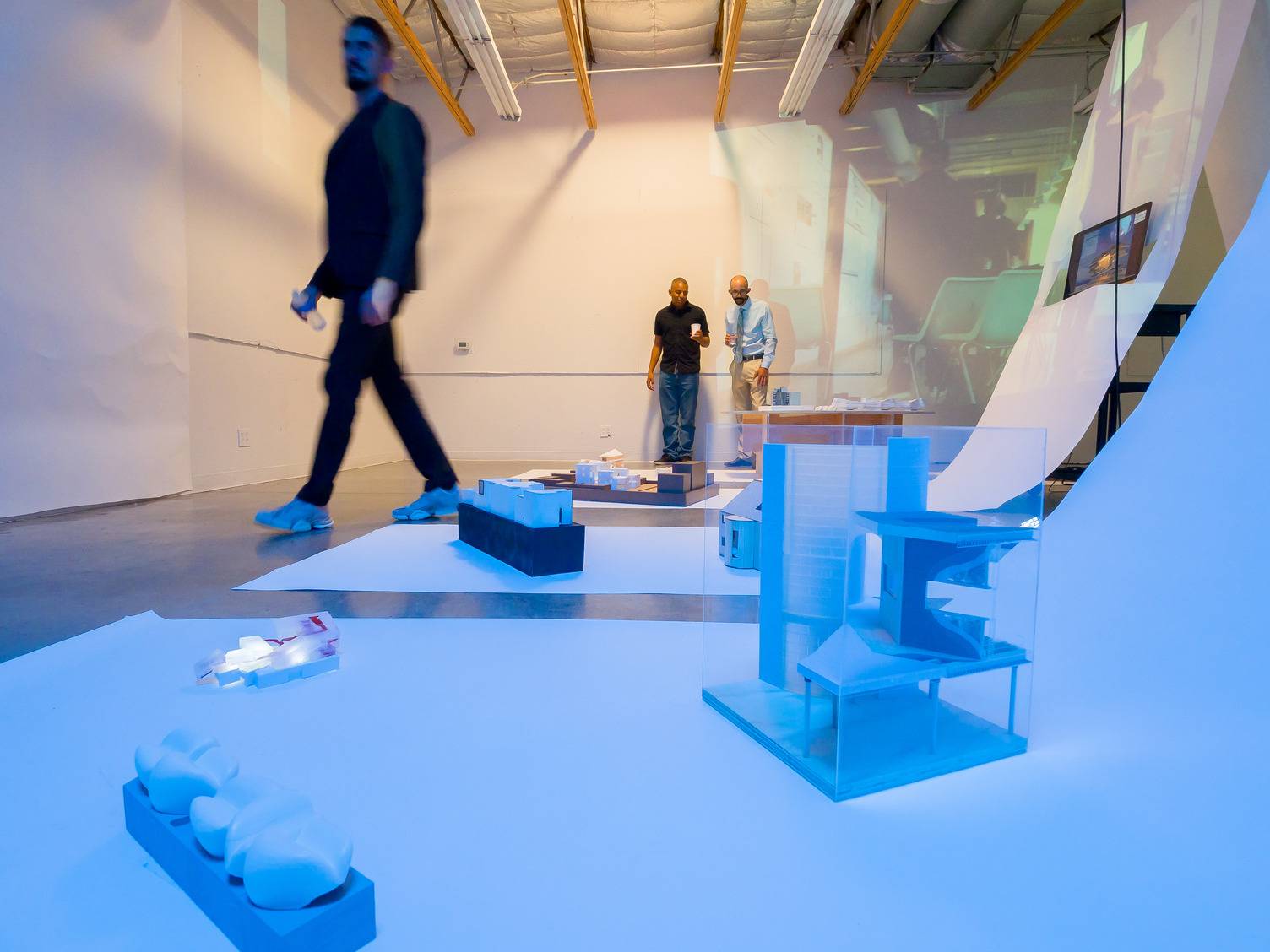 a group of people walking in a room with a large glass wall