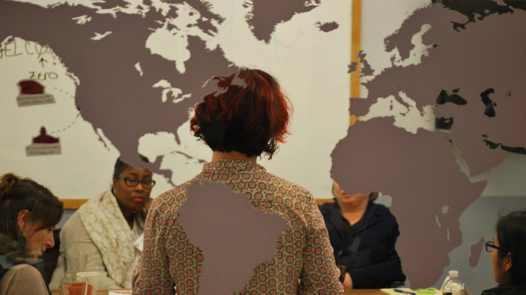 a group of people in a room with a map of the world