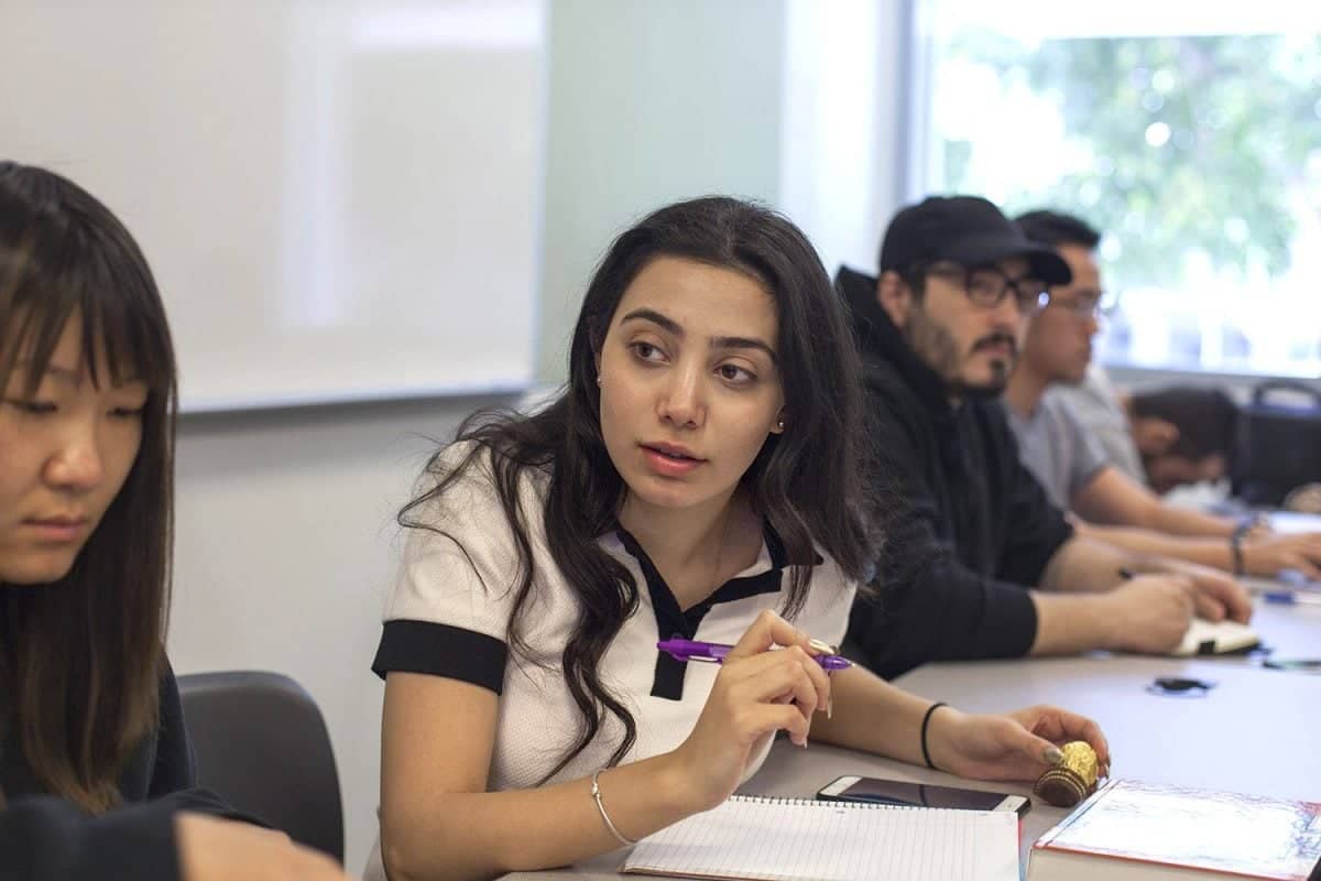 a person sitting at a table with other people in the background