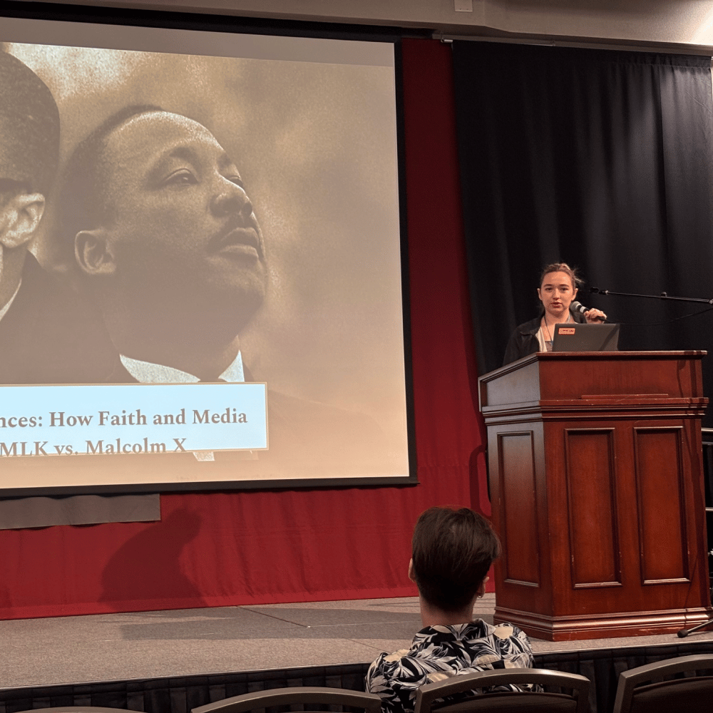 a person standing at a podium with a screen on the side