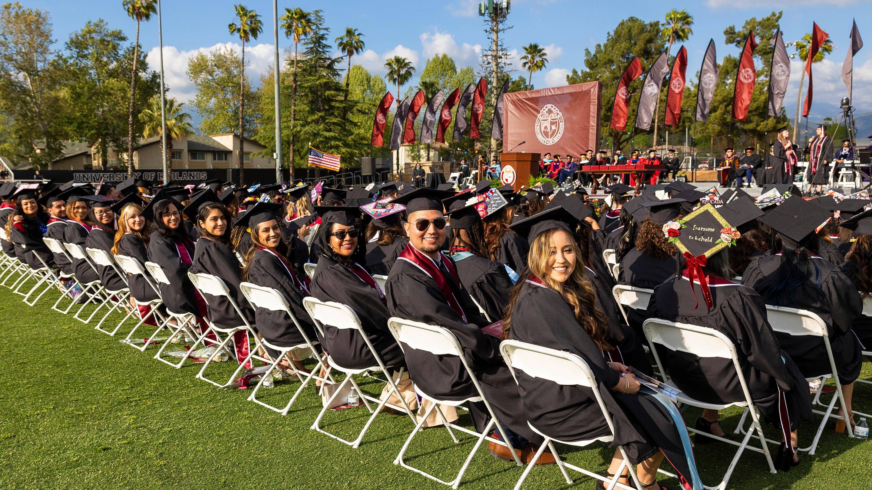 a group of people in graduation gowns and caps sitting in chairs