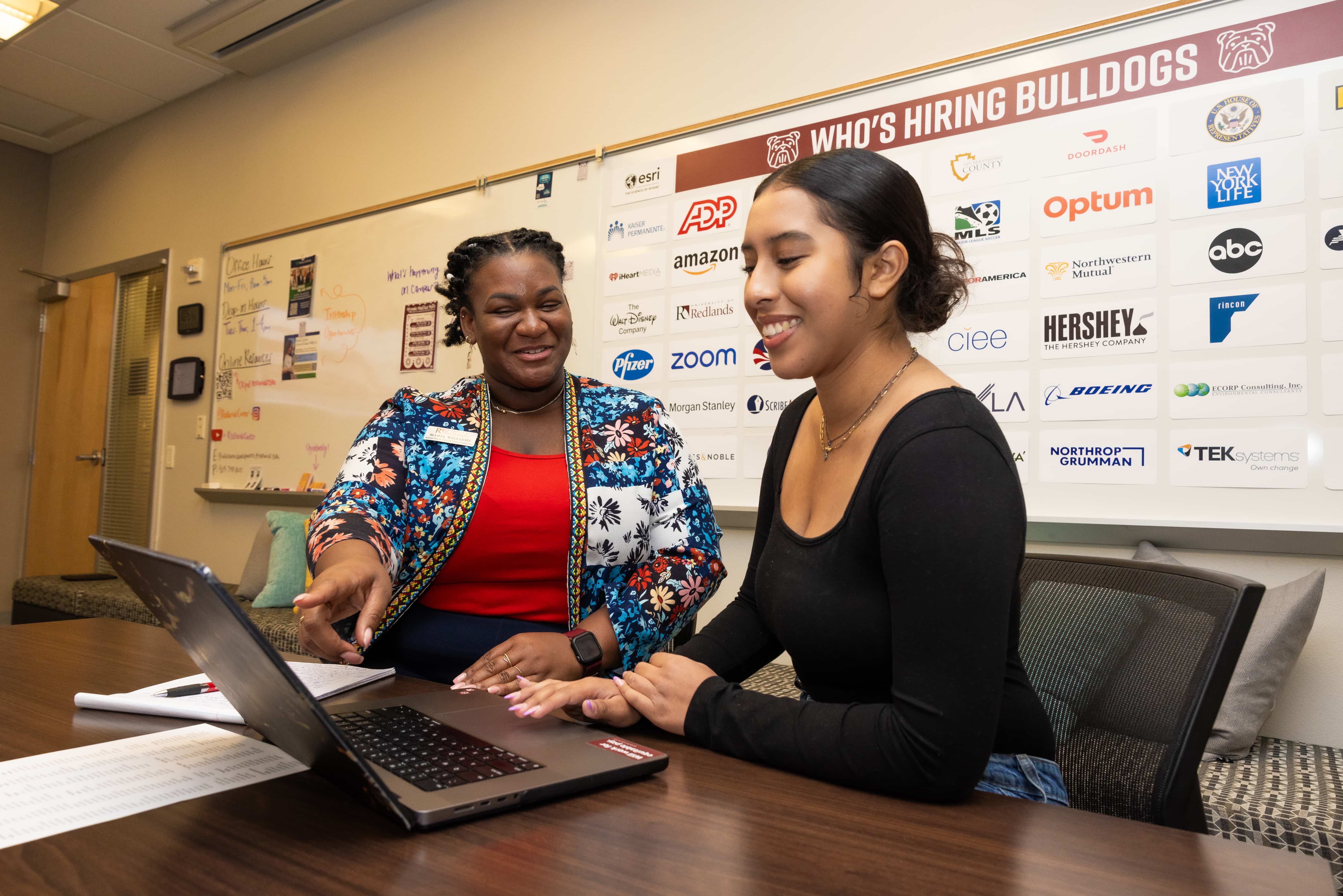 a person showing something to a person on a laptop