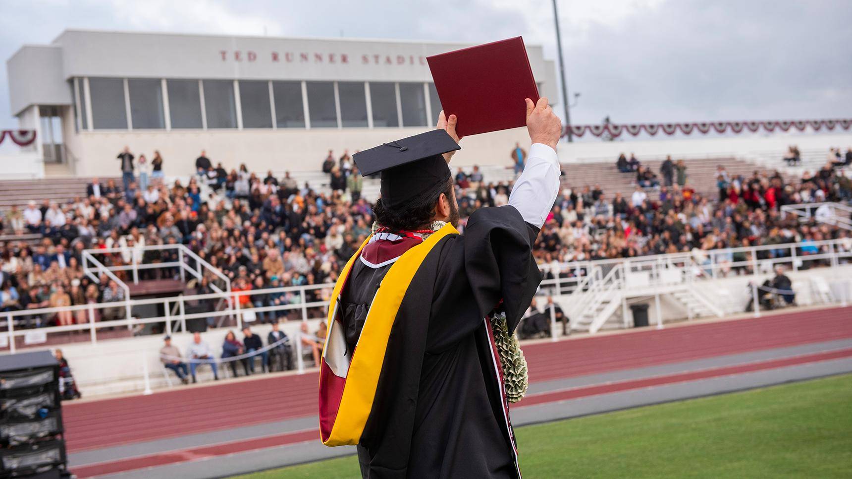 a person in a graduation gown holding a diploma