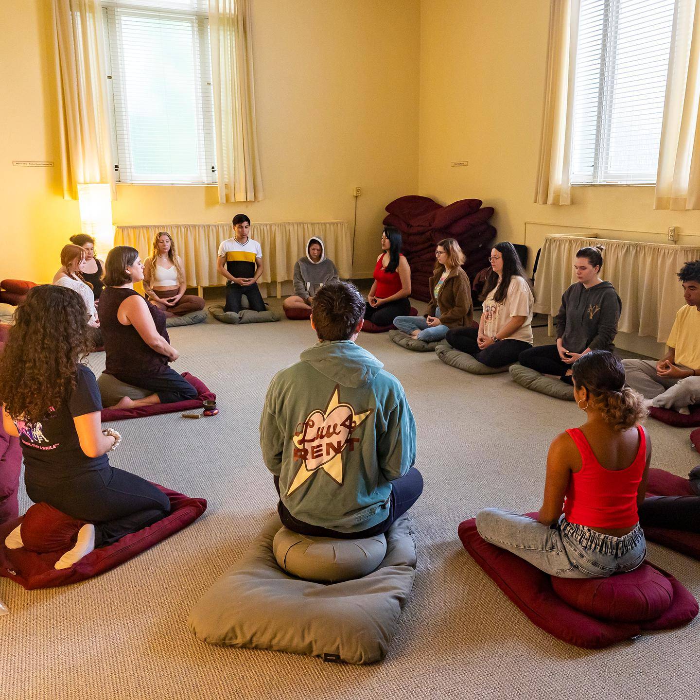 a group of people sitting on floor in a circle