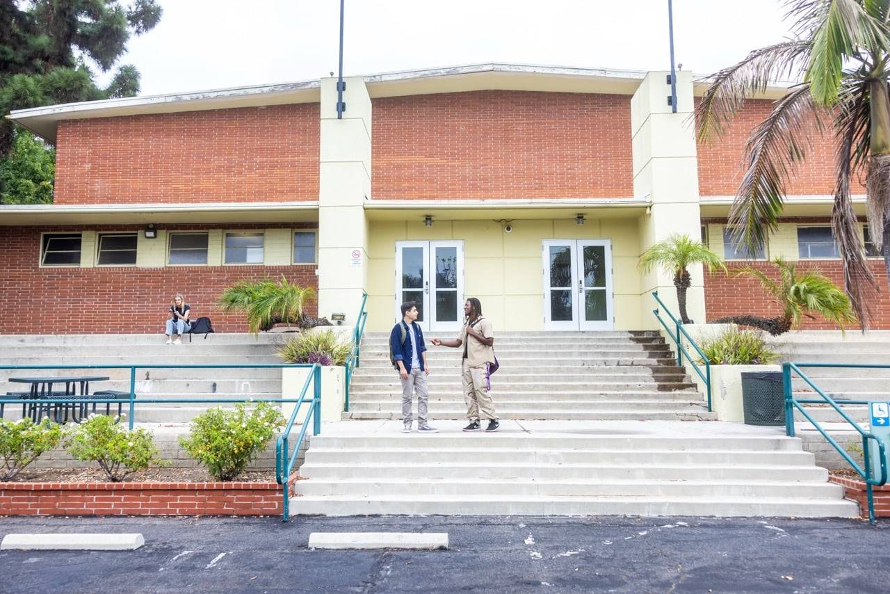 two men shaking hands in front of a building
