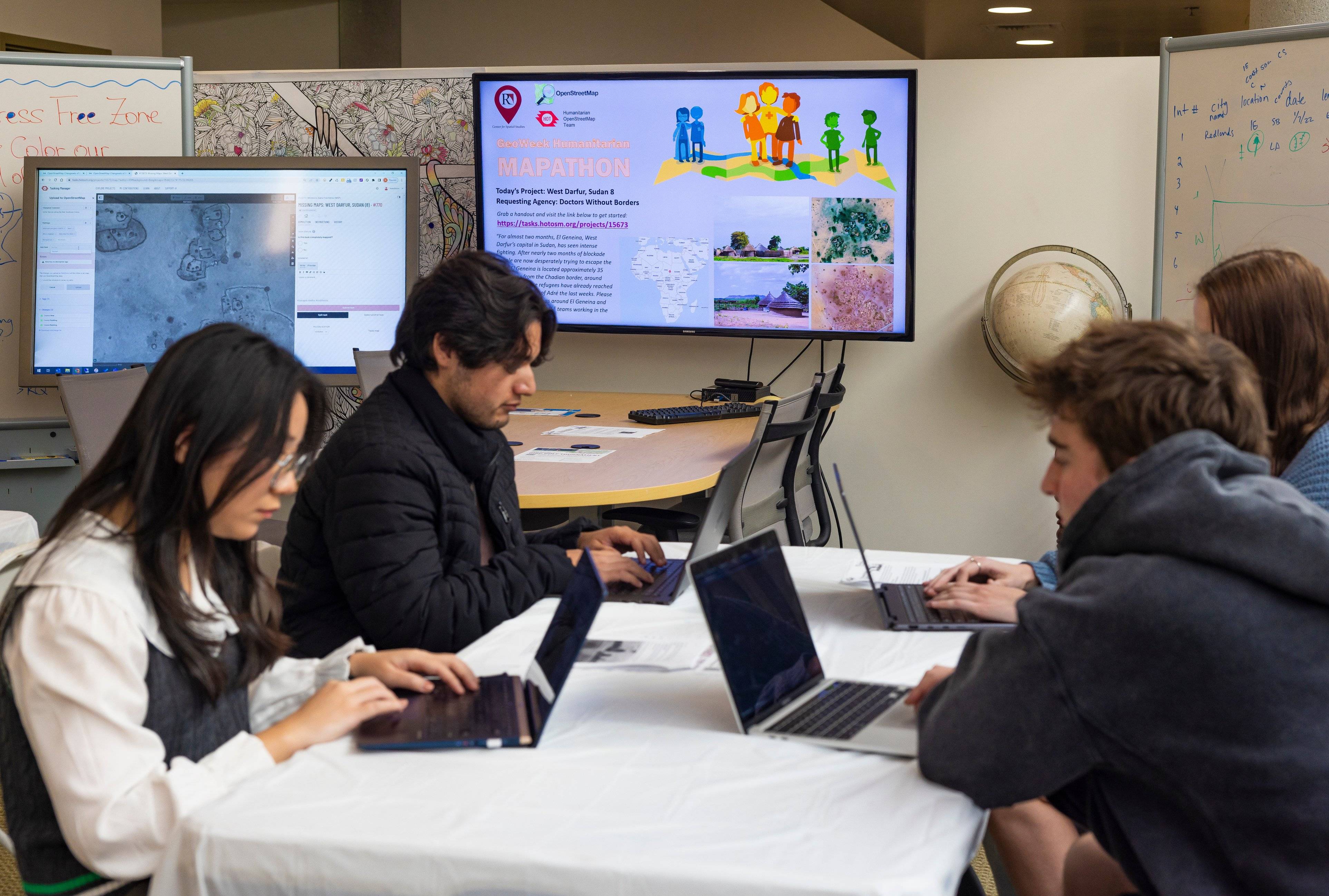 a group of people sitting at a table with laptops