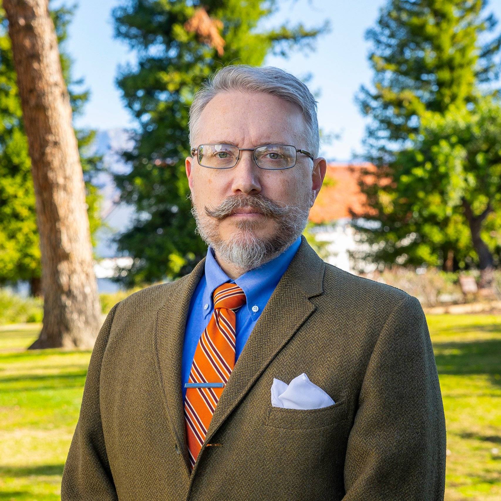 a person with a beard and mustache wearing a suit and tie