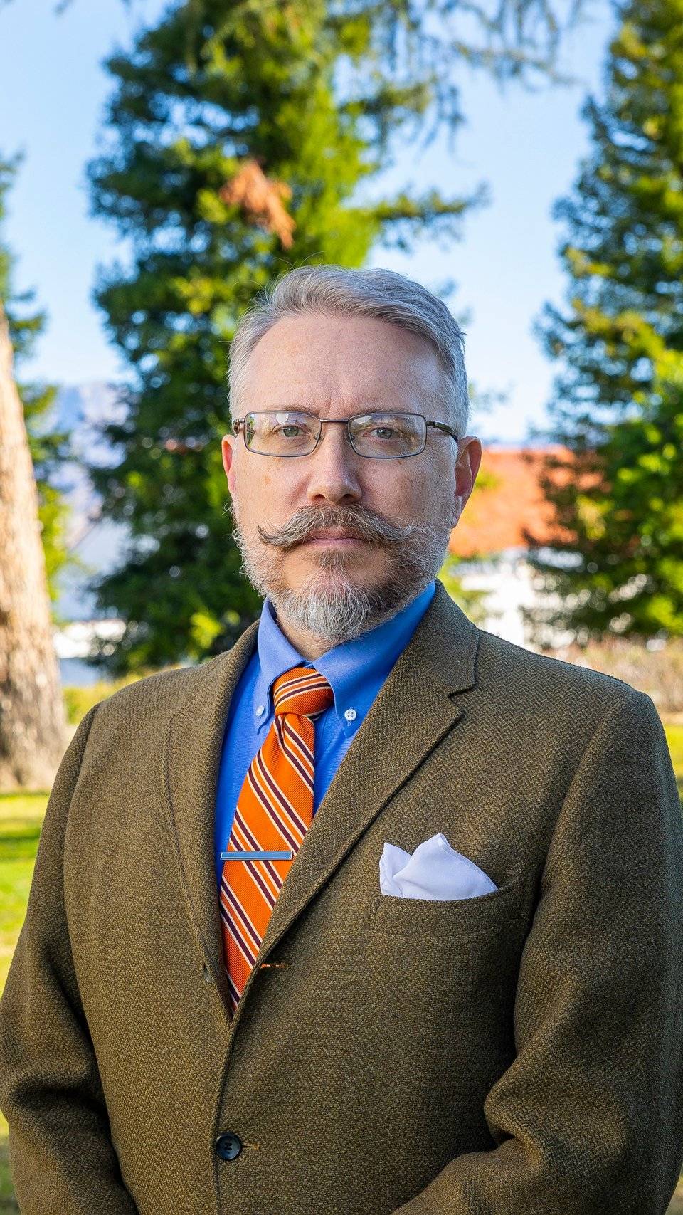 a person with a mustache and beard wearing a suit and tie