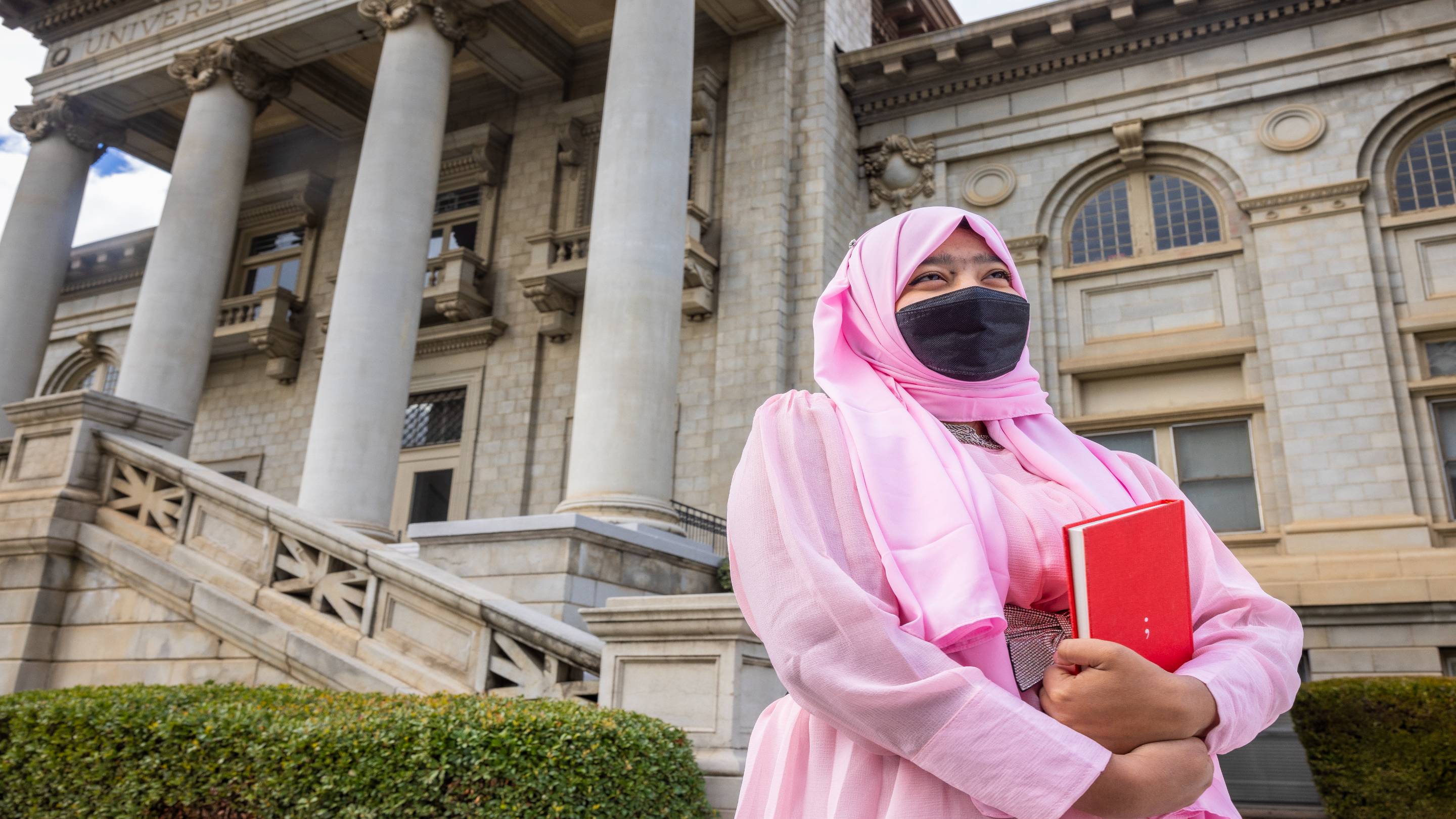 a person wearing a face mask and holding a book