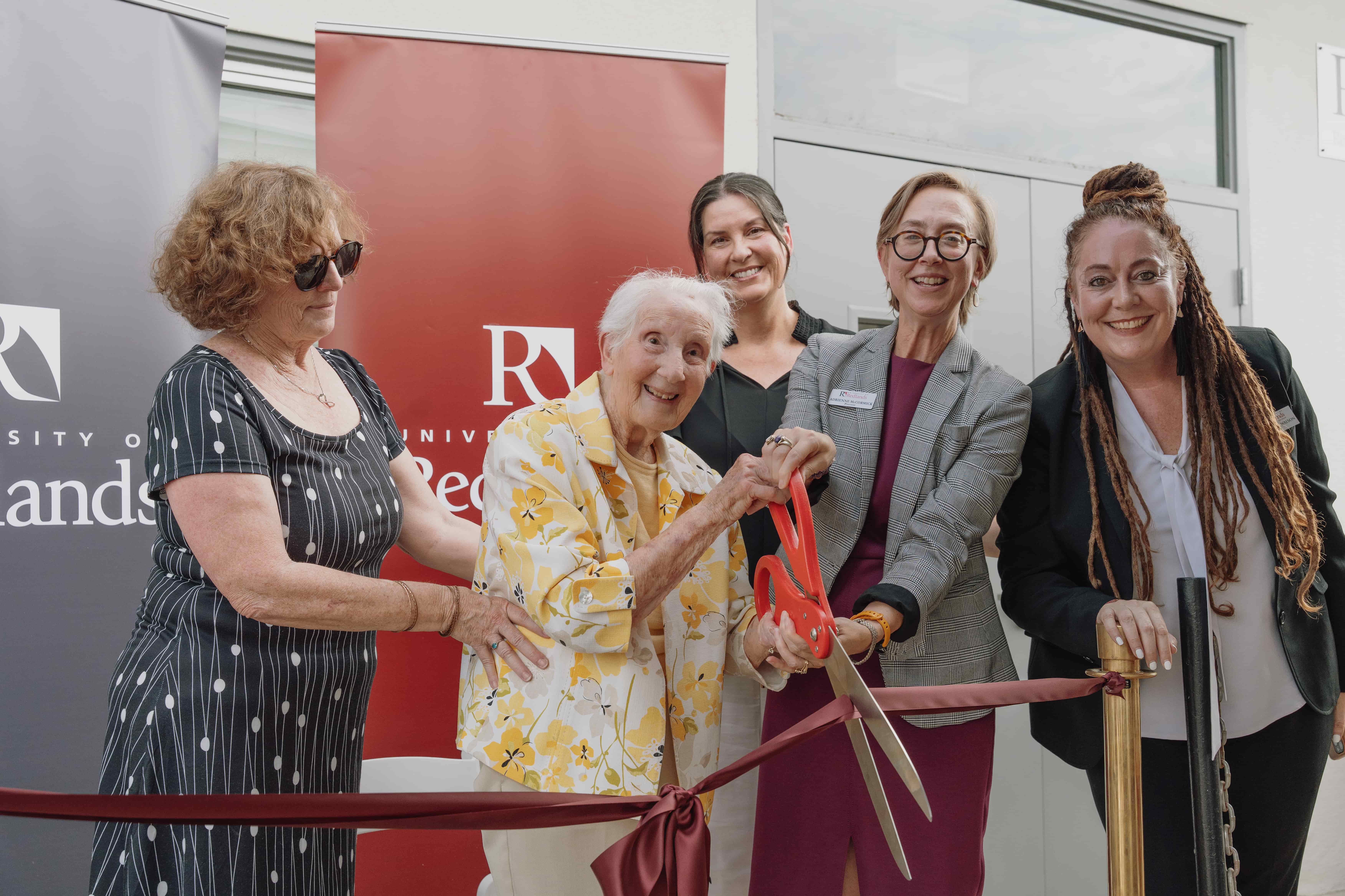 a group of women cutting a ribbon