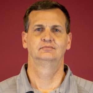 a person with short brown hair wearing a grey shirt