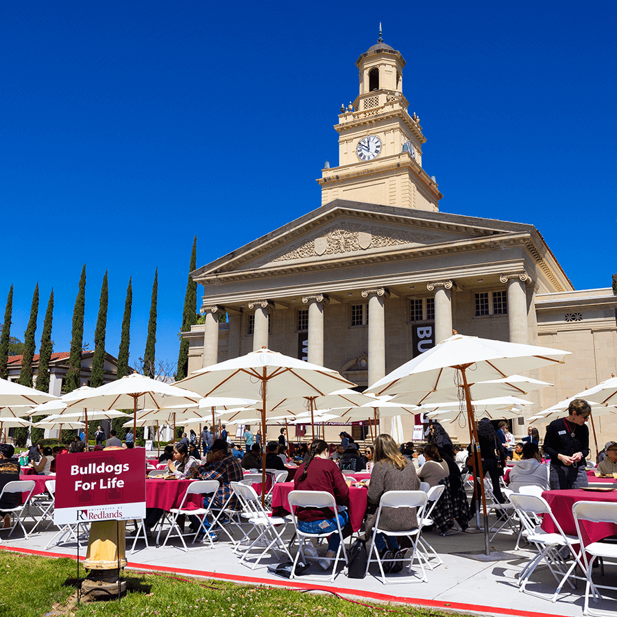 a group of people sitting outside tables and umbrellas