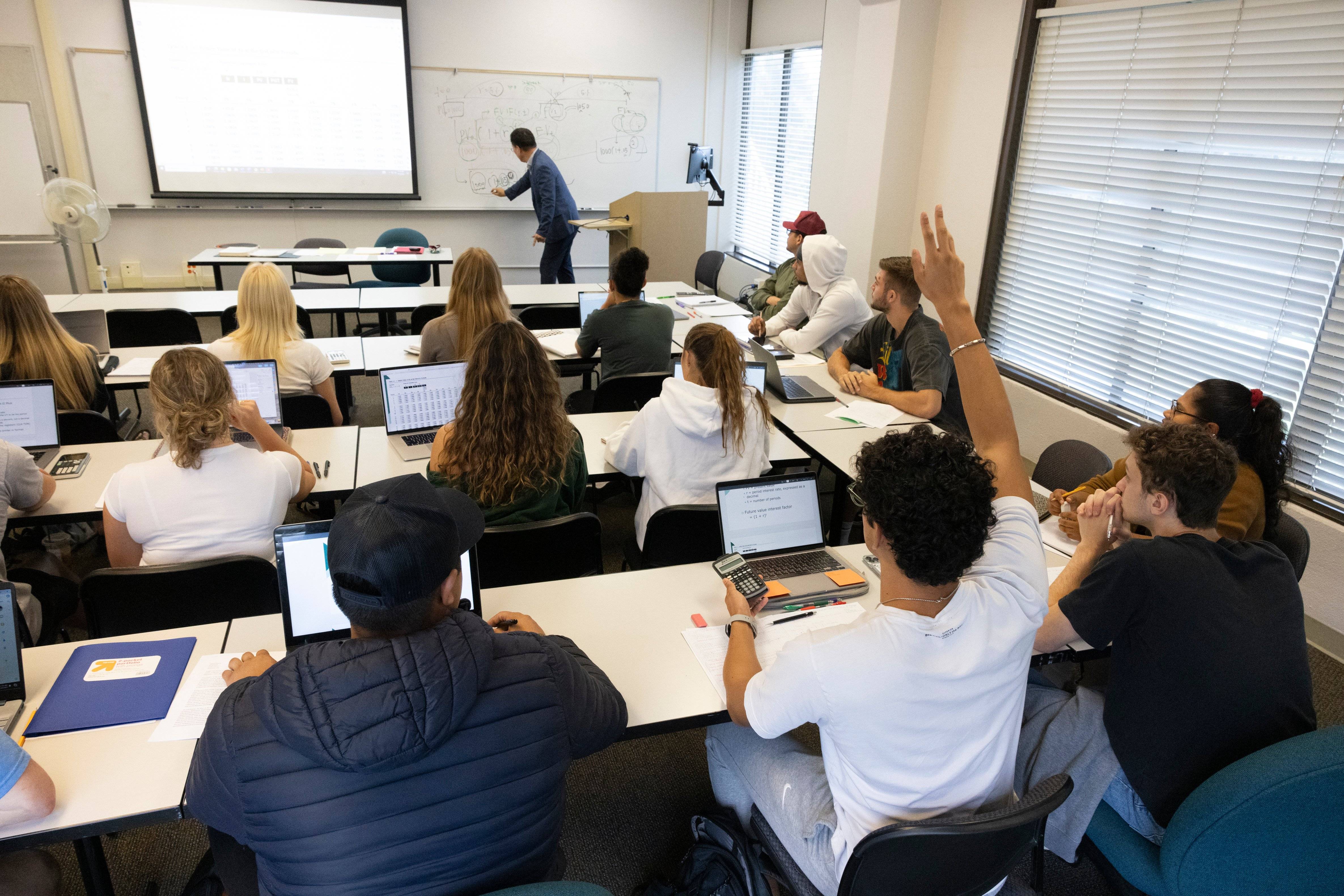 a person standing in front of a classroom with a group of people