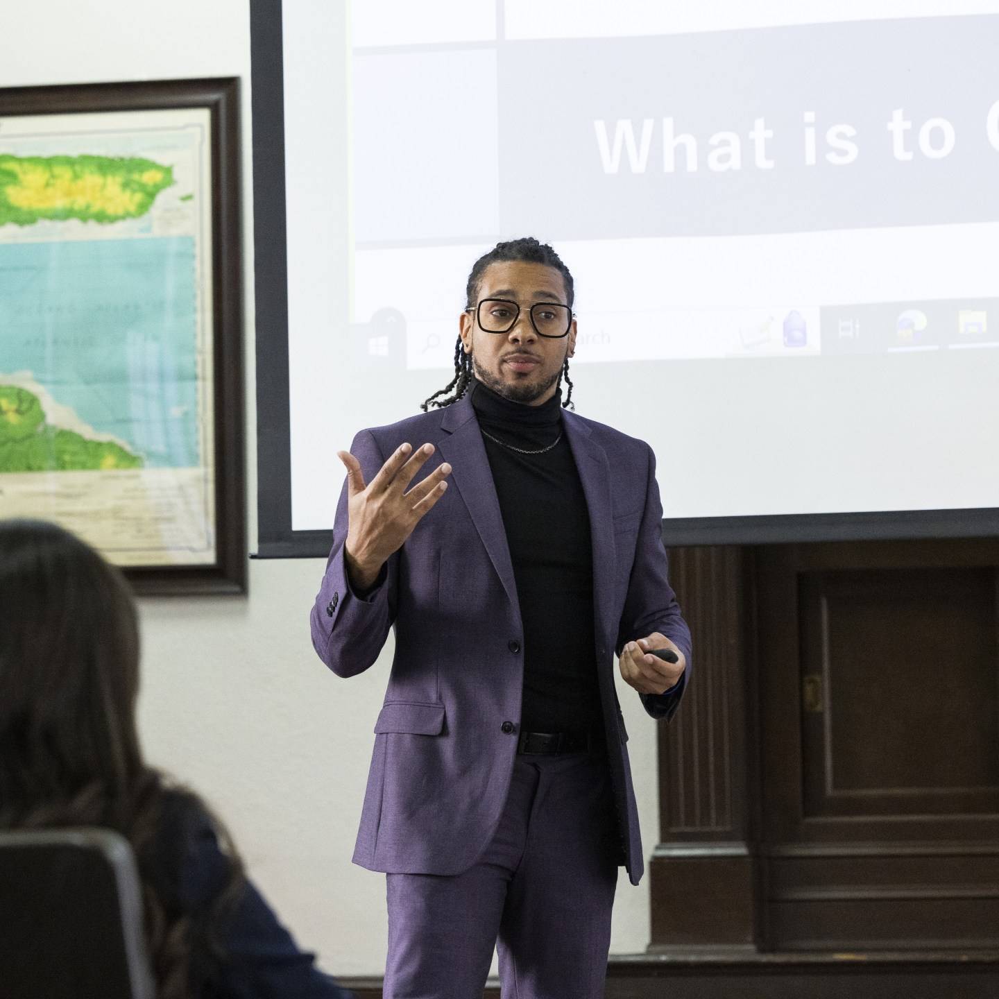 a person in a purple suit standing in front of a projection screen
