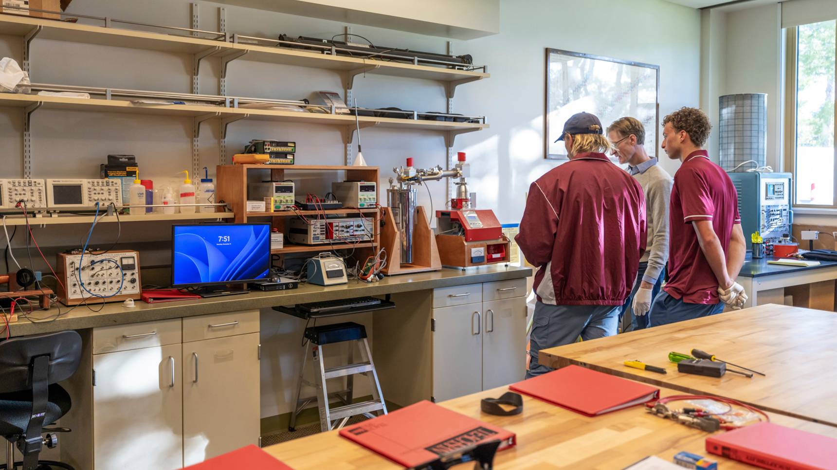 a group of men standing in a room with a computer