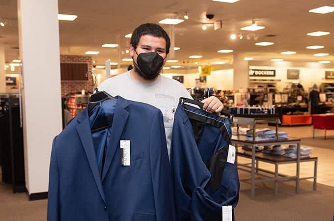 a person wearing a face mask holding a pair of suits