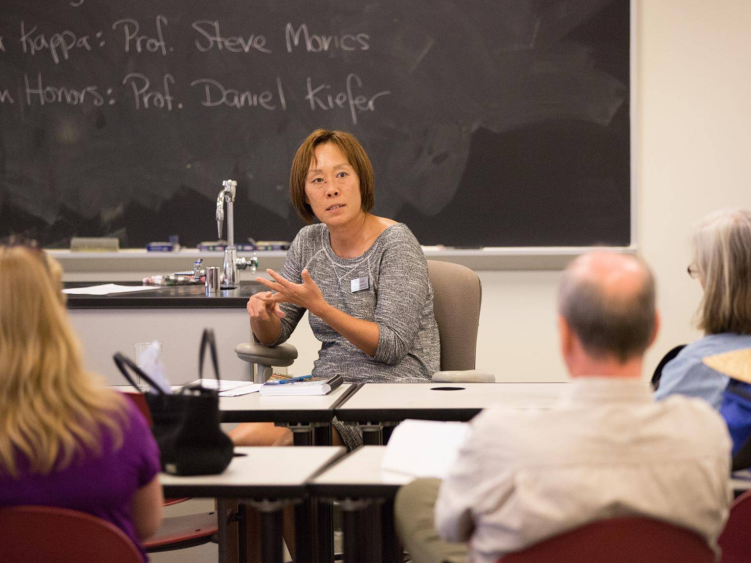 a person sitting at a desk in front of a chalkboard