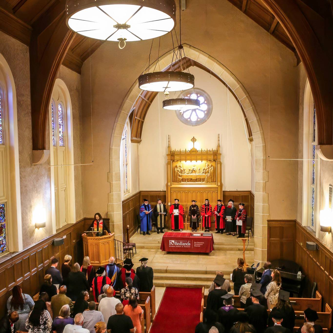Friends and family standing up for Commencement at a chapel.