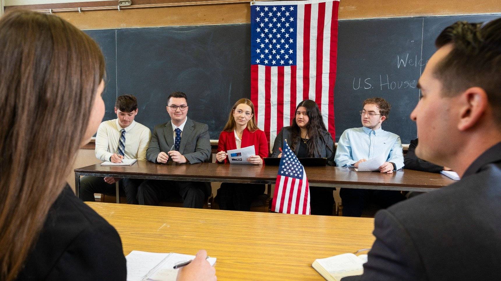 a group of people sitting at a table with flags behind them