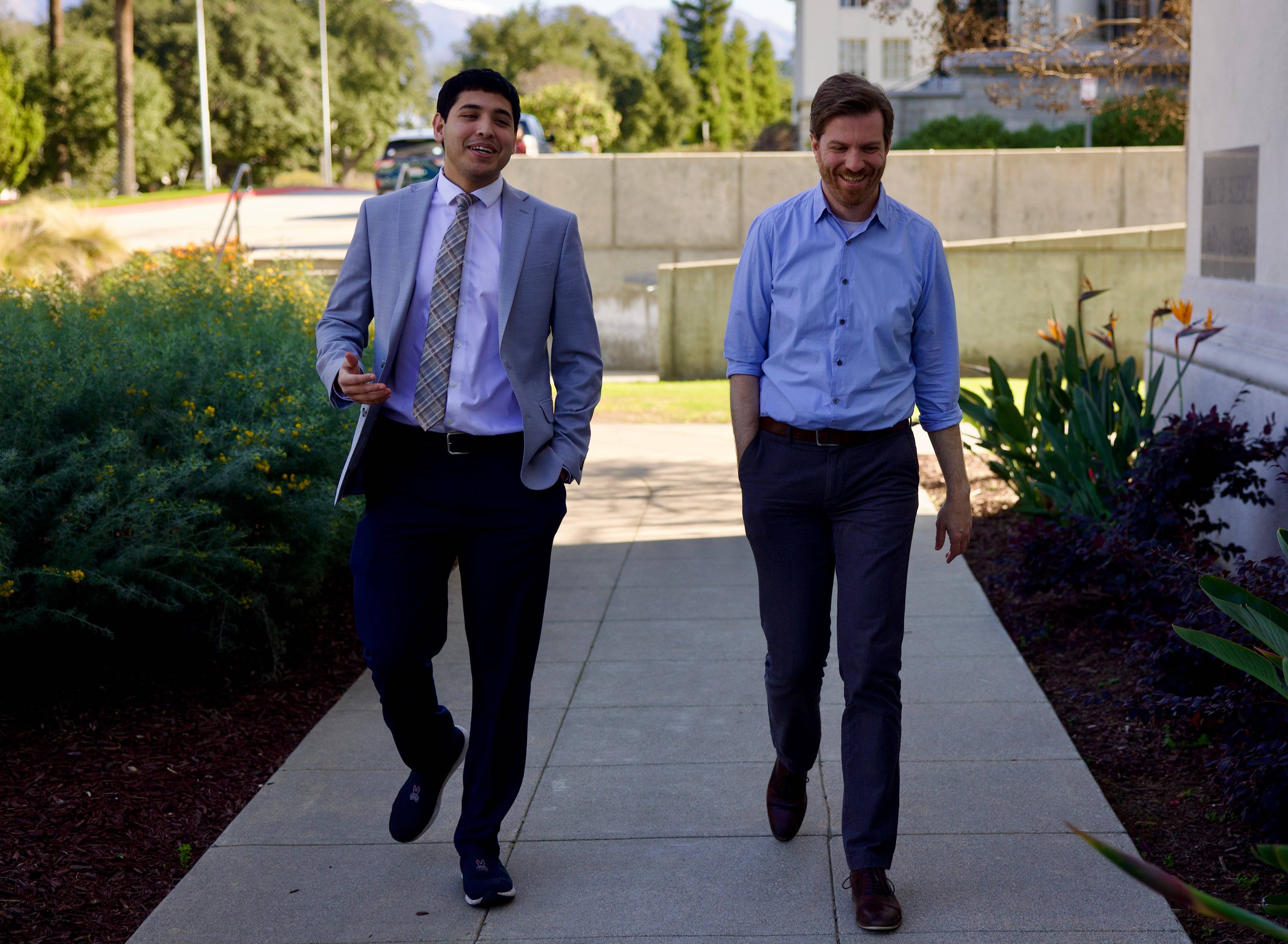 two men walking on a sidewalk